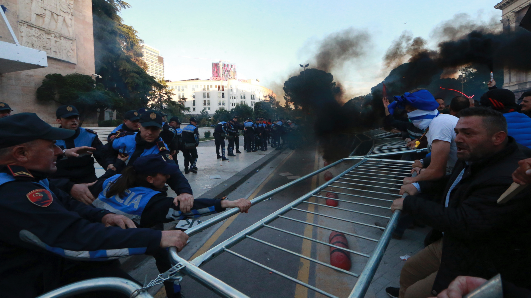 Protesters try to remove a metal fence during clashes with police outside the Government building in Tirana, Saturday, May 11, 2019. Thousands of supporters of the Albania's center-right opposition protested in Tirana Saturday, calling for the left-wing government to resign and for an early parliamentary election. (AP Photo/Hektor Pustina)
