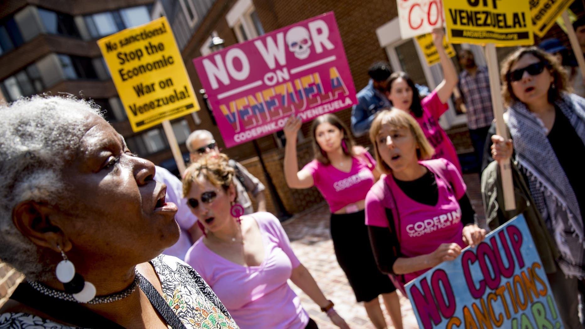 U.S. activist Medea Benjamin, co-founder of the antiwar group Code Pink, second from right, and others, sing together outside the Venezuelan Embassy in Washington on Thursday. Supporters of interim government opposition leader Juan Guaido have blocked the entrances to the embassy, cutting off supplies to backers of embattled leader Nicolas Maduro supporters occupying the building. (AP Photo/Andrew Harnik)