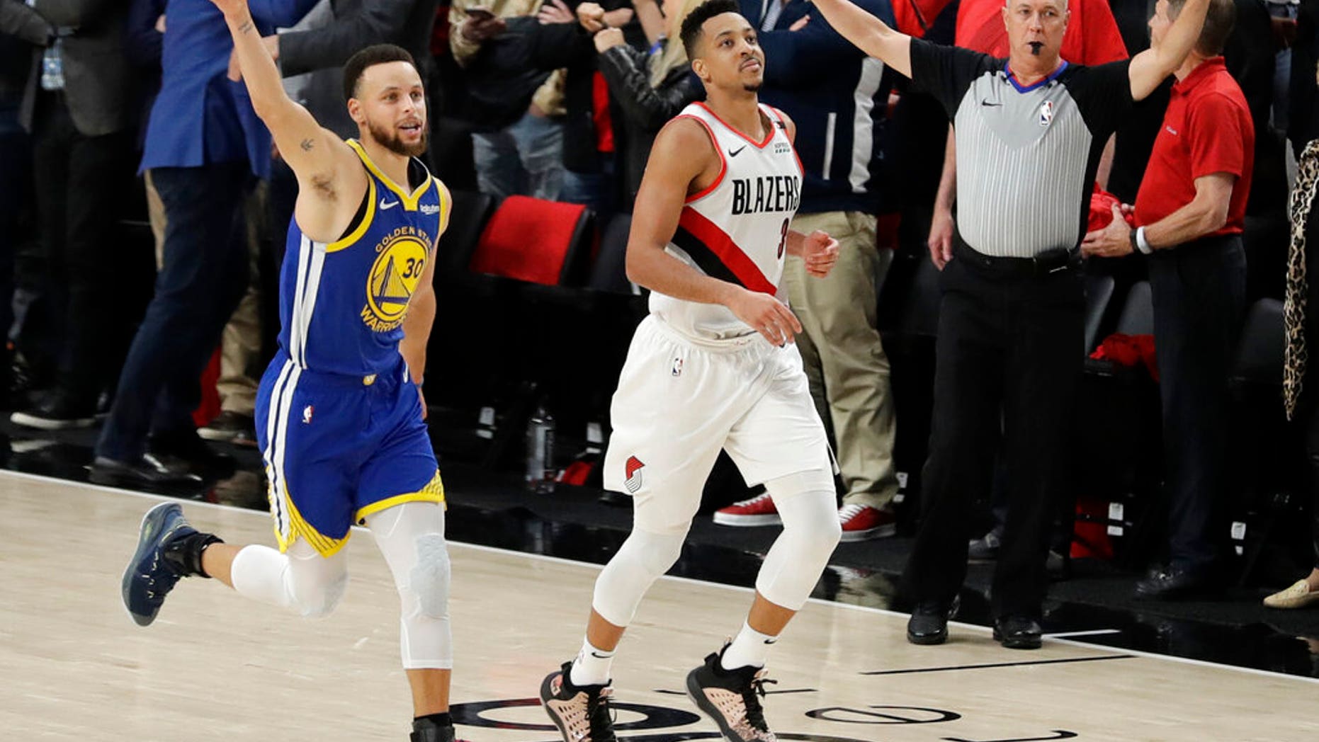 Golden State Warriors guard Stephen Curry, left, celebrates as he runs next to Portland Trail Blazers guard CJ McCollum, center, at the end of Game 4 of the NBA basketball playoffs Western Conference finals.