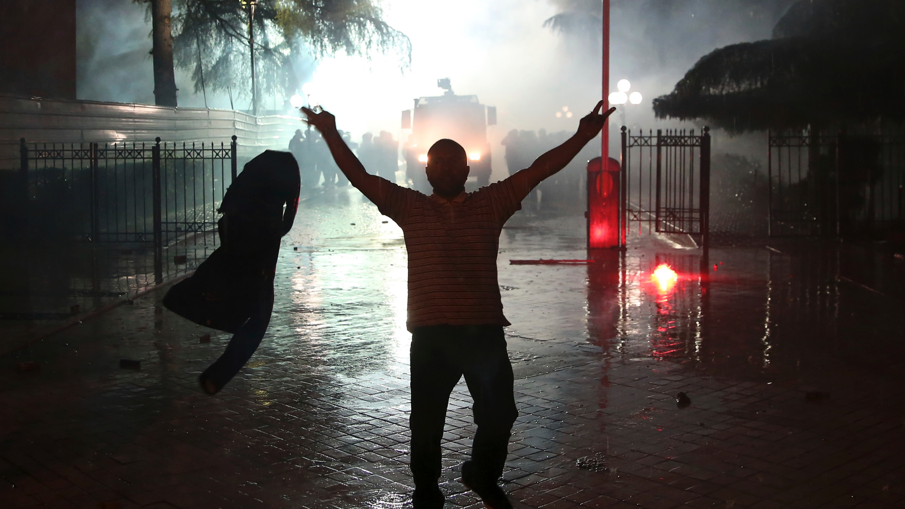 A protester gestures during clashes near the Parliament building in Tirana, Monday, May 13, 2019. Anti-government protesters in Albania hurled firebombs and flares at riot officers standing in front of the main government building and national police headquarters Monday, hours after the U.S. and European Union lawmakers called for restraint. (AP Photo/Visar Kryeziu)