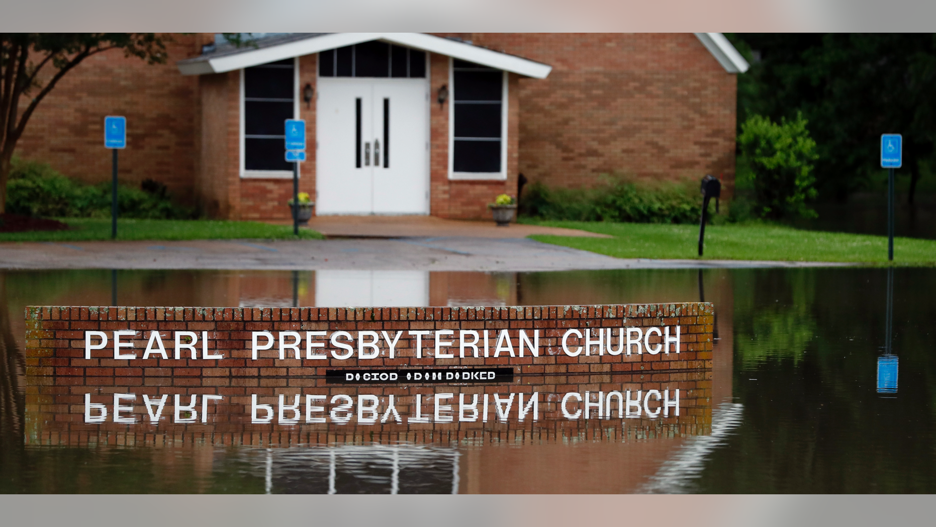 The Pearl Presbyterian Church's sign is reflected in floodwaters in Pearl, Miss., on Thursday, May 9, 2019. There is no pond on the property and the flash flooding filled up the parking lot as it surrounded the church. Strong winds, tornado warnings and substantial rains added to the flash flooding throughout Mississippi including this area of downtown Jackson, Miss., Thursday, May 9, 2019. (AP Photo/Rogelio V. Solis)
