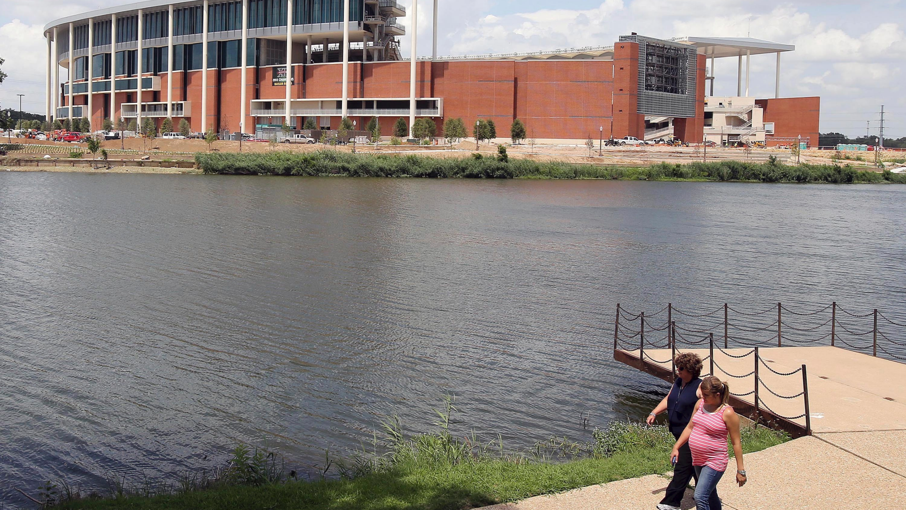 FILE - In this July 2, 2014, file photo, people stroll along the river across from the new McClane Stadium at Baylor University in Waco, Texas. Baylor University has announced a $100 million donation that administrators say is the largest gift in school history. The announcement Saturday night, May 4, 2019, in Waco, said the donor wishes to remain anonymous with the donation earmarked for Baylor's $1.1 billion Give Light philanthropic campaign that includes teaching, research and service. Baylor is the world's largest Baptist university, with enrollment of about 17,000. (Jerry Larson/Waco Tribune-Herald via AP, File)