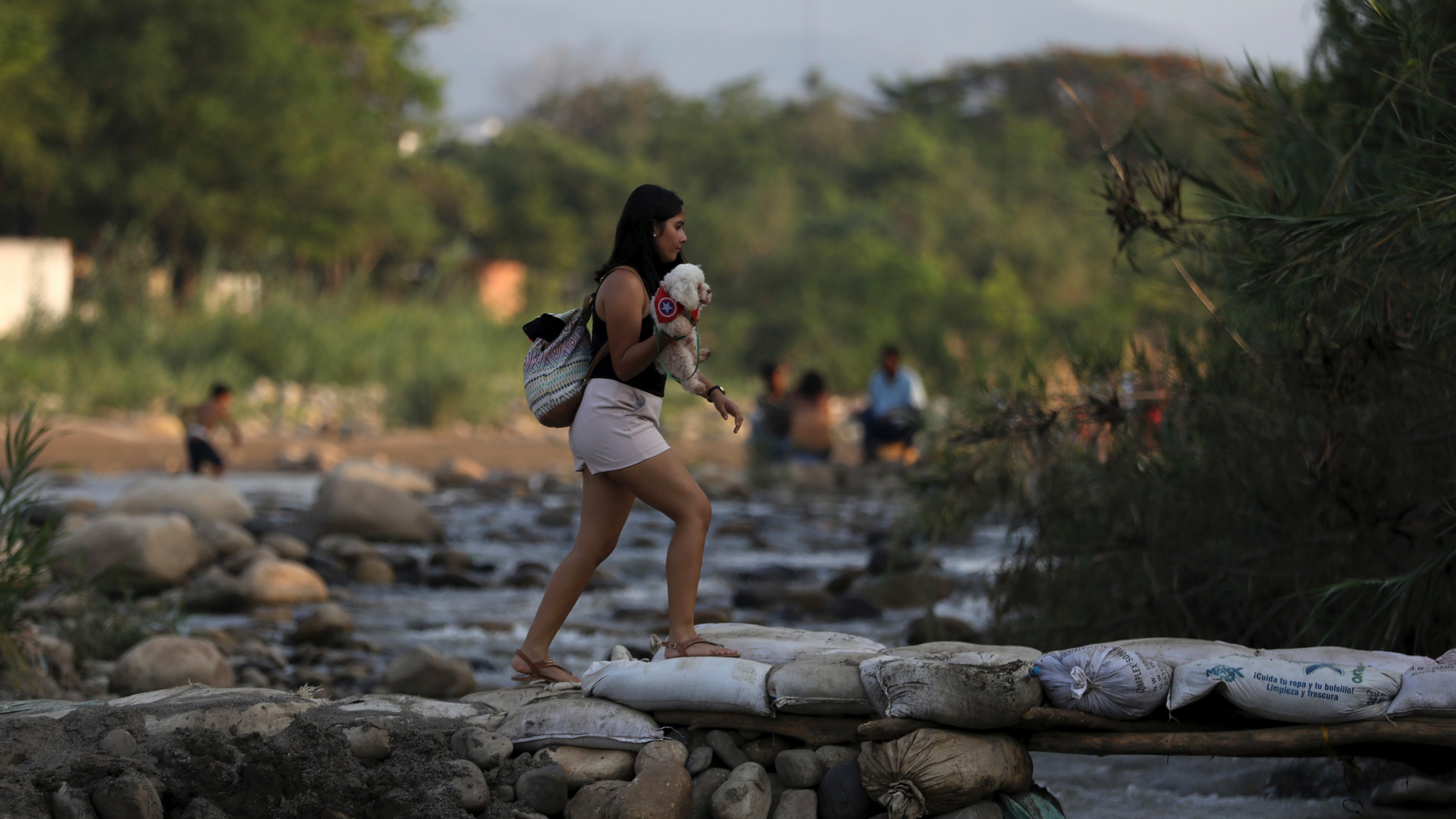 A woman holding her pet crosses illegally into Colombia near the Simon Bolivar International Bridge in La Parada near Cucuta, Colombia, Wednesday, May 1, 2019, on the border with Venezuela. The border area near Cucuta was peaceful Wednesday, even as Venezuelans heeded opposition leader Juan Guaidó's call to fill streets around the nation but security forces showed no sign of backing his cry for a widespread military uprising, instead dispersing crowds with tear gas as the political crisis threatened to deepen. (AP Photo/Fernando Vergara)