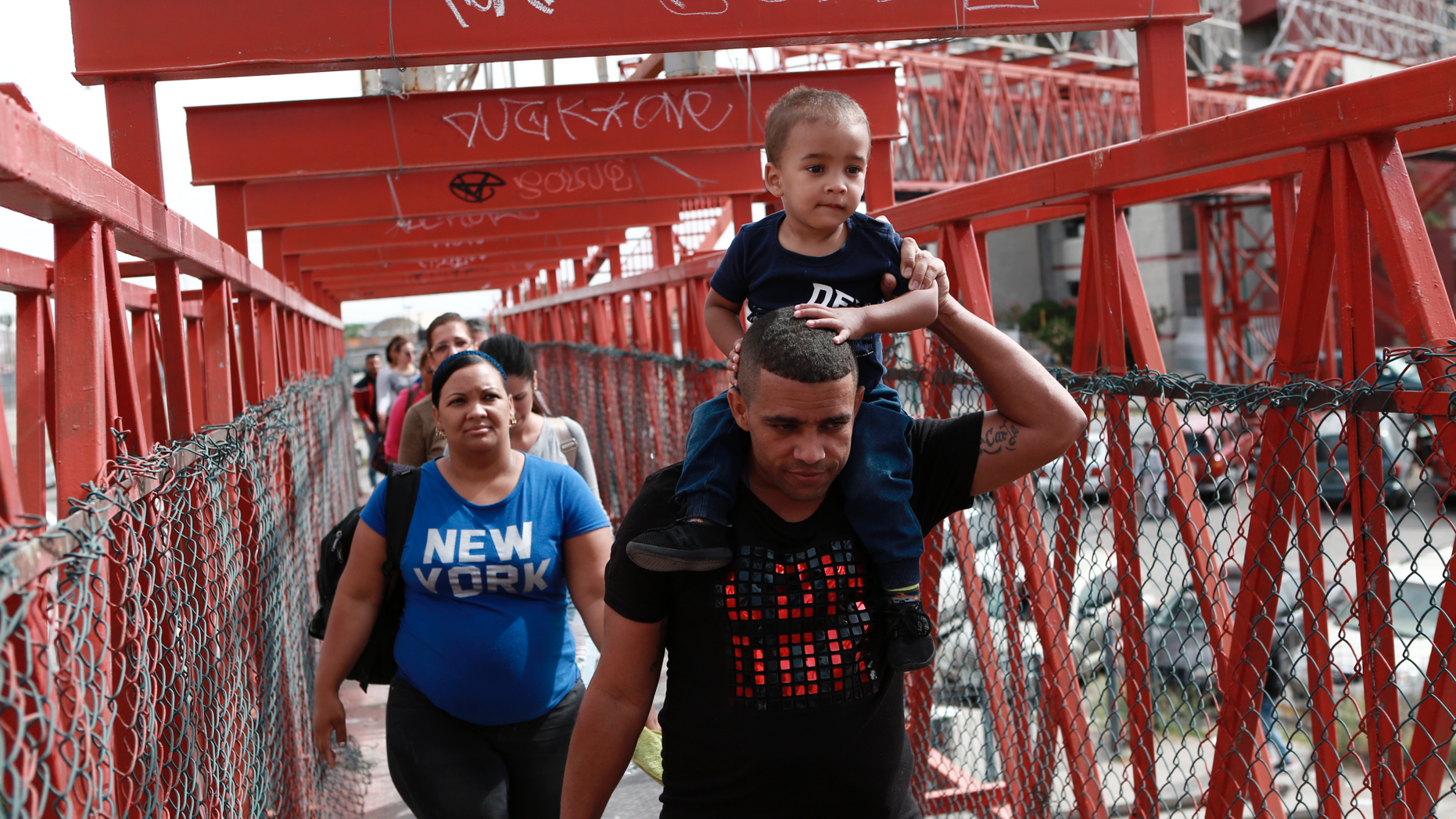 In this April 29, 2019, photo, Cuban migrants are escorted in Ciudad Juarez, Mexico, by Mexican immigration officials as they cross the Paso del Norte International bridge to be processed as asylum seekers on the U.S. side of the border. U.S. authorities have been telling asylum seekers that they are at capacity and to return when space opens up, a hands-off approach that has created haphazard and often-dubious arrangements in Mexico. (AP Photo/Christian Torres)