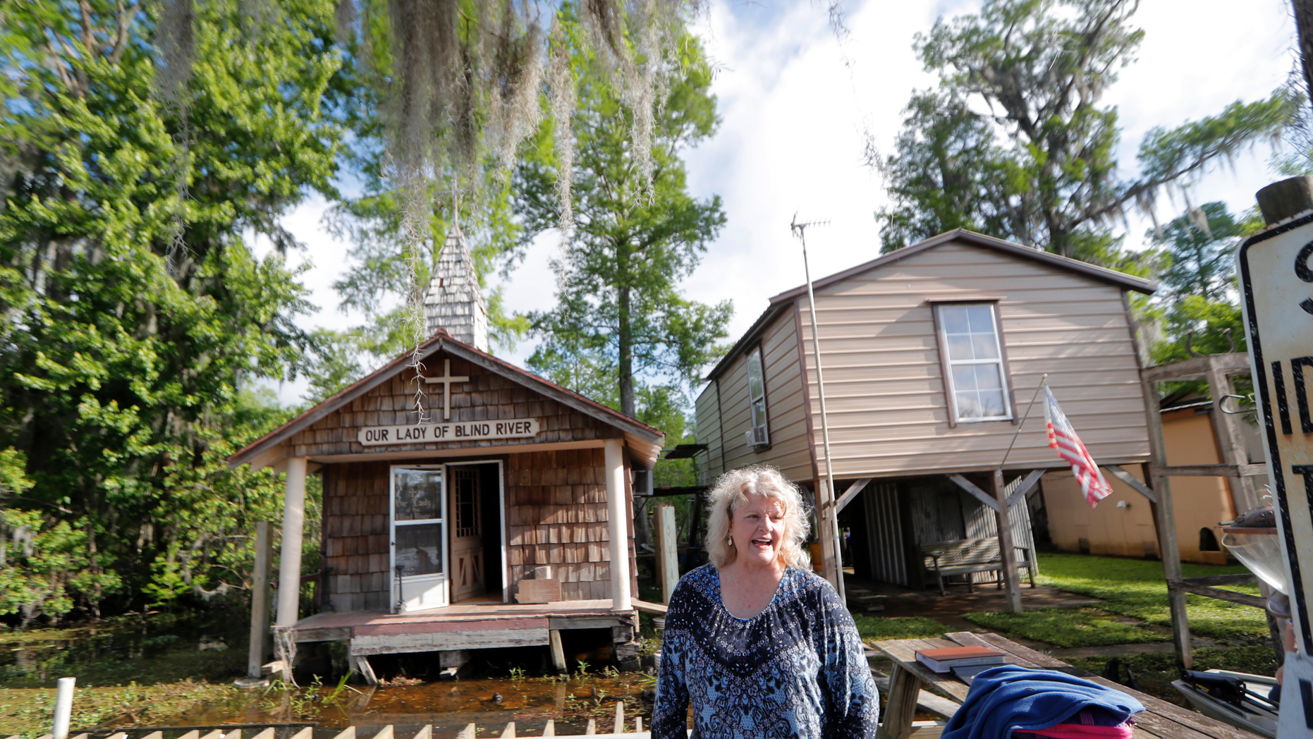 Pat Hymel stands on the dock in front of Our Lady of Blind River Chapel, along Blind River in St. James Parish, La., Tuesday, April 9, 2019. The chapel was built decades ago by her parents, Martha Deroche and her husband Bobby, after Martha had a vision of Jesus kneeling by a rock. Over the years, people have stopped by in boats or kayaks to pray in the one-room chapel. But floods over the years have damaged the little church, and the couple's grandson Lance Weber had to close it about two years ago out of safety concerns. (AP Photo/Gerald Herbert)