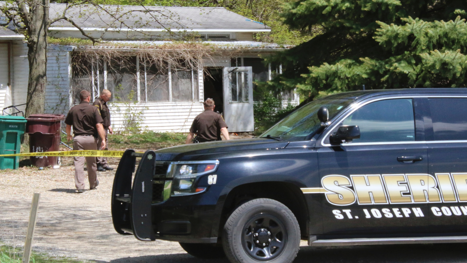 In this Monday, May 6, 2019 photo, St. Joseph County Sheriff deputies stand outside the site where a woman was fatally shot in Fawn River Township, Mich. Authorities say a 9-year-old is suspected in the shooting of a woman in her southern Michigan home. (Corky Emrick/Sturgis Journal via AP)