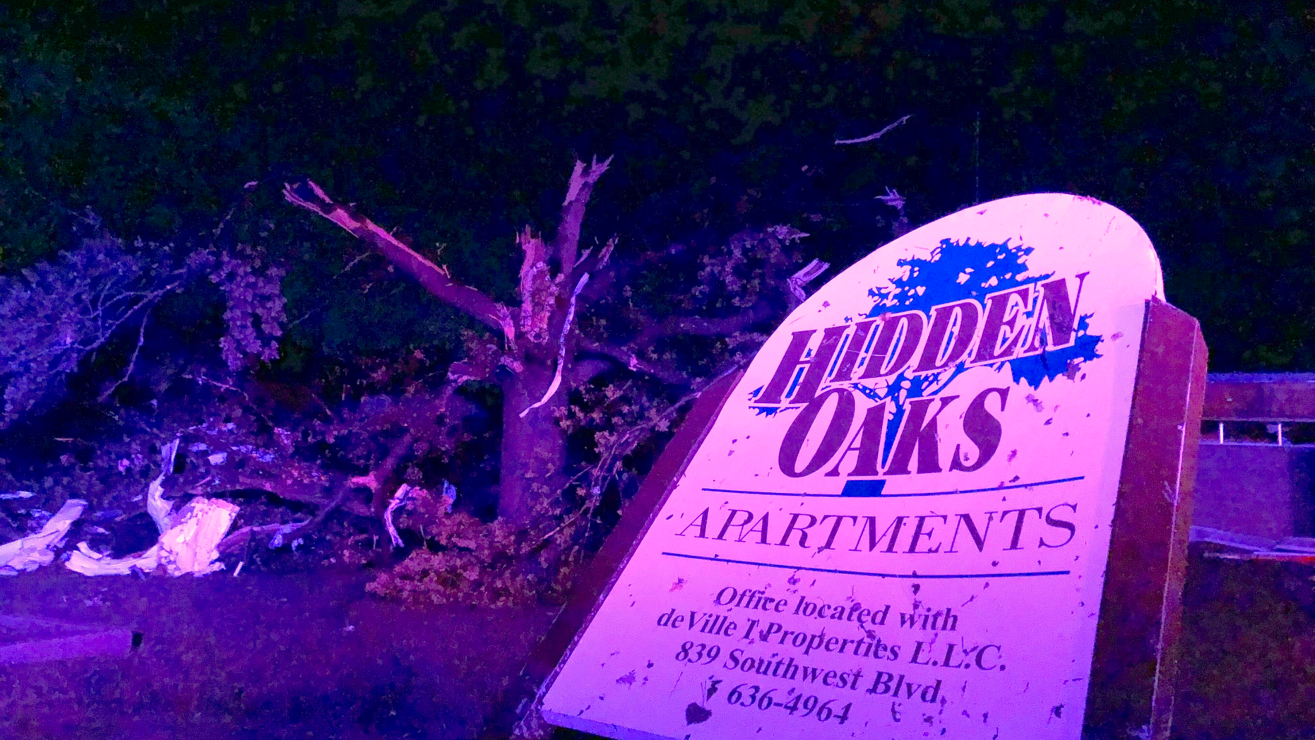 The sign for the Hidden Oaks apartment complex in Jefferson City Missouri stands bent on May 23, 2019, from an apparent tornado in front of a tree that was ripped apart. A "violent tornado" touched down in Jefferson City, Missouri, causing possible fatalities, according to the National Weather Service (AP Photo/David A. Lieb)