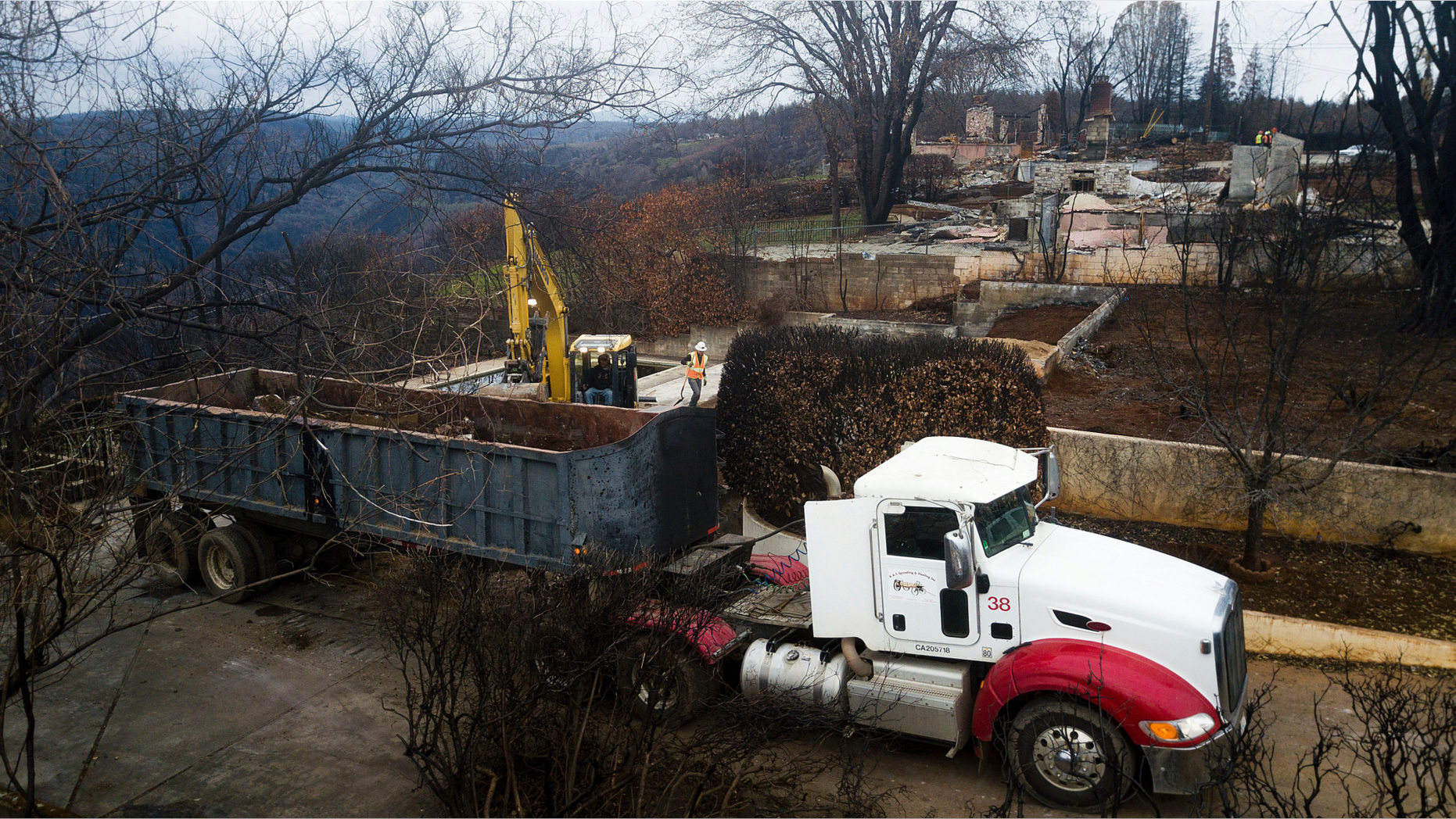 FILE - In this Feb. 8, 2019 file photo, an excavator loads debris onto a truck while clearing a property burned by the Camp Fire in Paradise, Calif. Fears of harming an endangered frog species have forced crews to delay cleaning debris from about 800 properties in Paradise, angering some residents anxious to start rebuilding their homes. (AP Photo/Noah Berger, File)