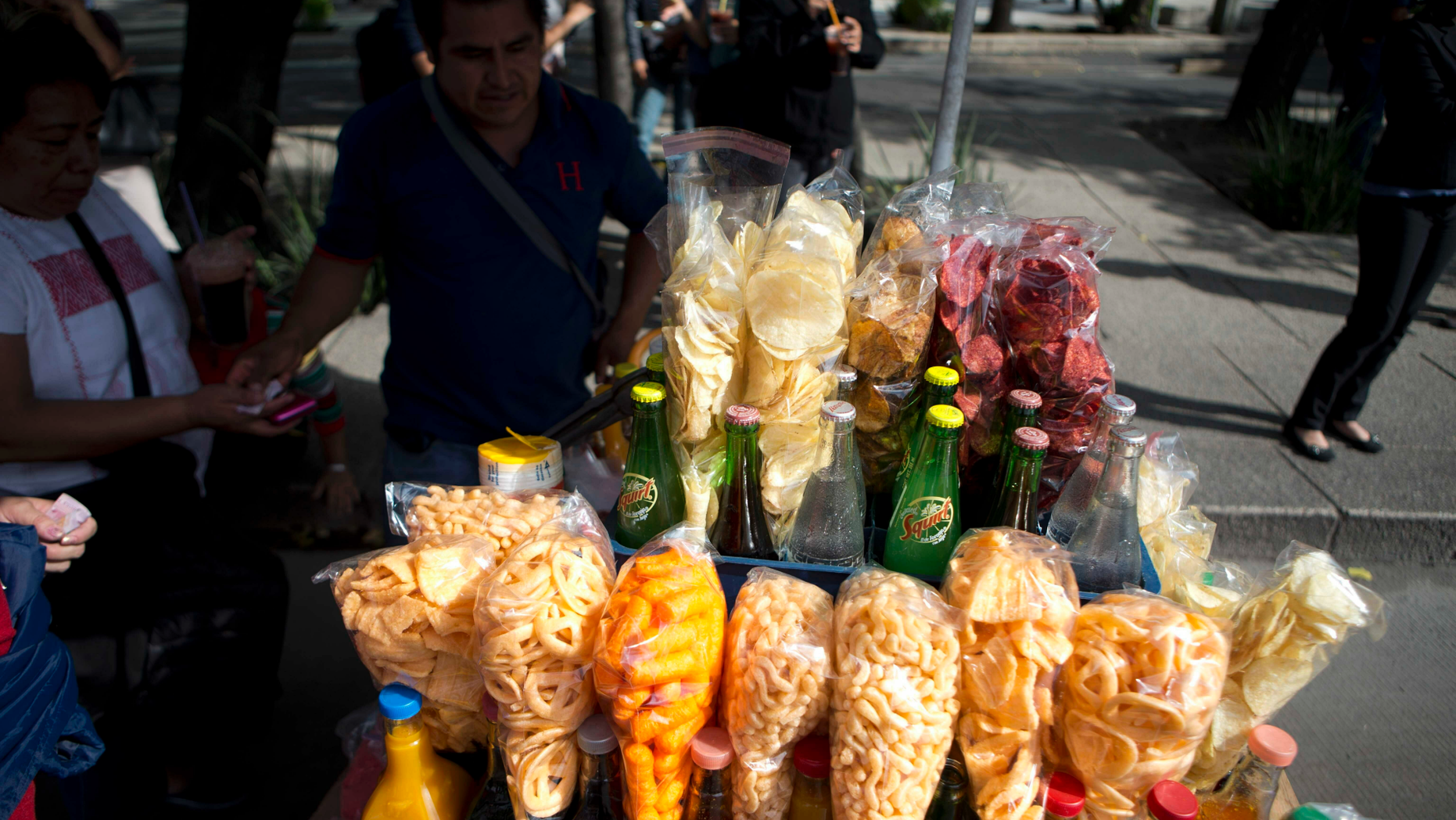 FILE - In this July 5, 2016 file photo, a street vendor sells fried snacks packaged in plastic bags in Mexico City. Mexico City lawmakers announced on Thursday, May 9, 2019 they have passed a ban on plastic bags, utensils and other disposable plastic items to take effect at the end of 2020, giving businesses more than a year to make the switch to biodegradable products. (AP Photo/Eduardo Verdugo, File)