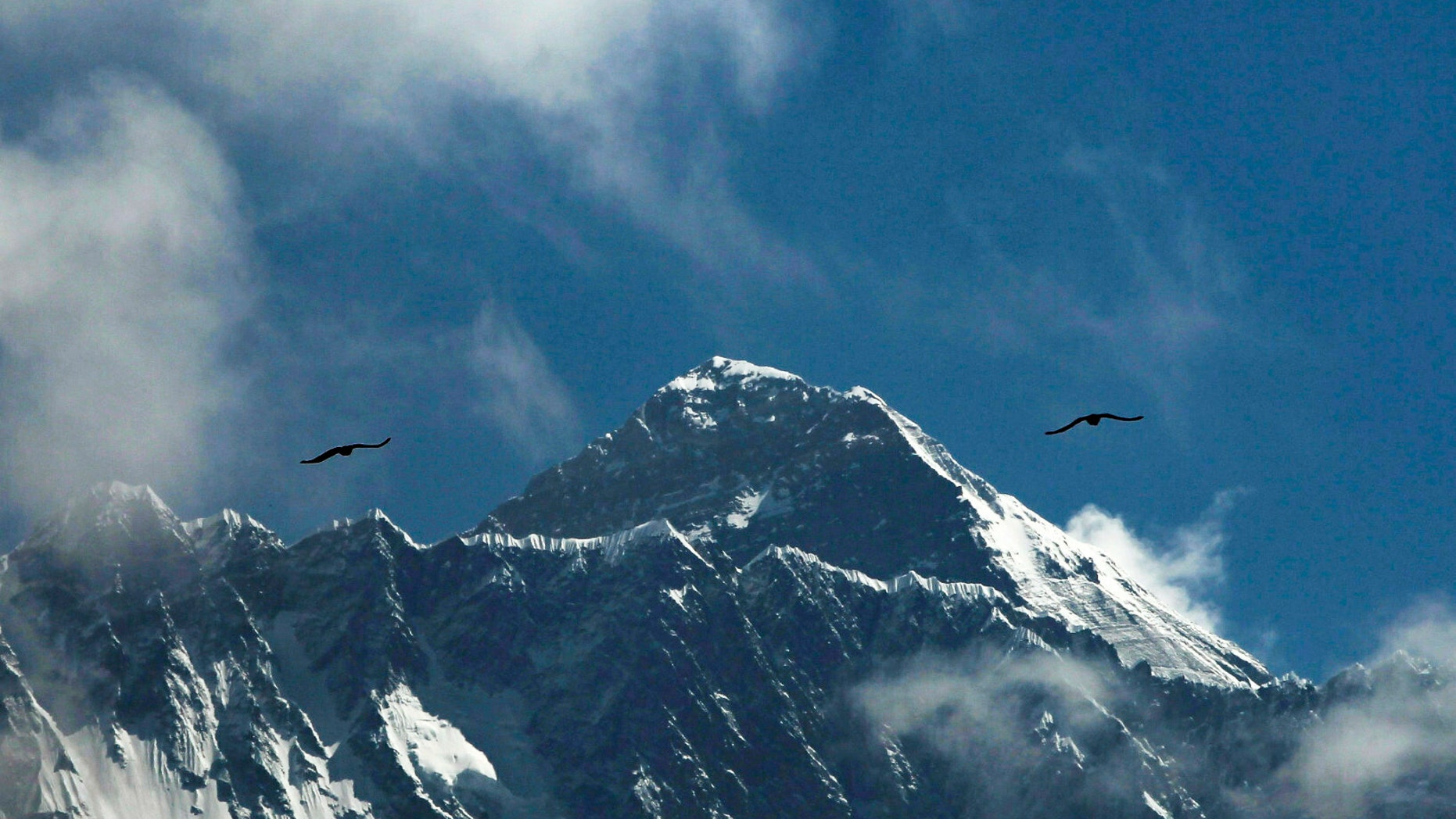 Birds fly as Mount Everest is seen from Namche Bajar, Solukhumbu district, Nepal, Monday, May 27, 2019. A Colorado climber died shortly after getting to the top of Mount Everest and achieving his dream of scaling the highest peaks on each of the seven continents, his brother said Monday. (AP Photo/Niranjan Shrestha)