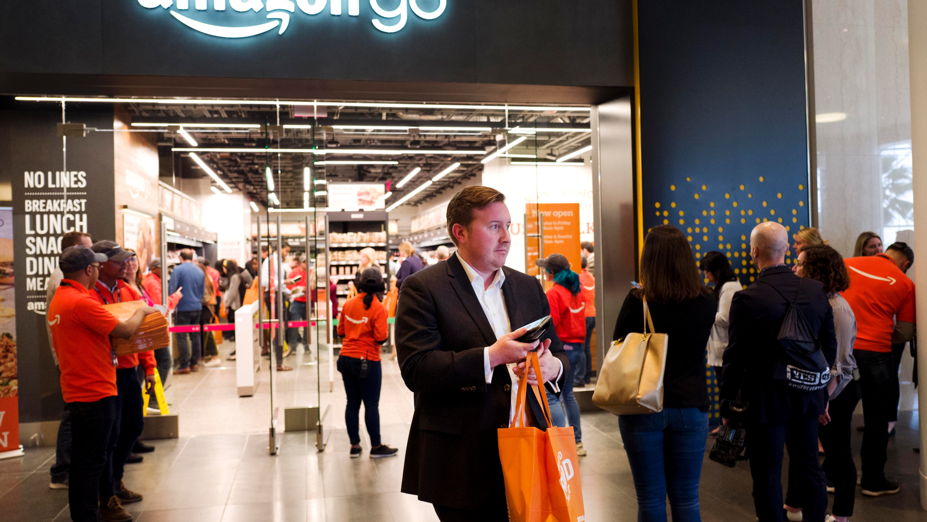 A customer carries his shopping bag as she walks out of a newly-opened Amazon Go store, Tuesday, May 7, 2019 in New York. The store will be the first Amazon Go store to accept cash. At its other shops, customers can only enter with an app that links to a credit card or an Amazon account.(AP Photo/Mark Lennihan)