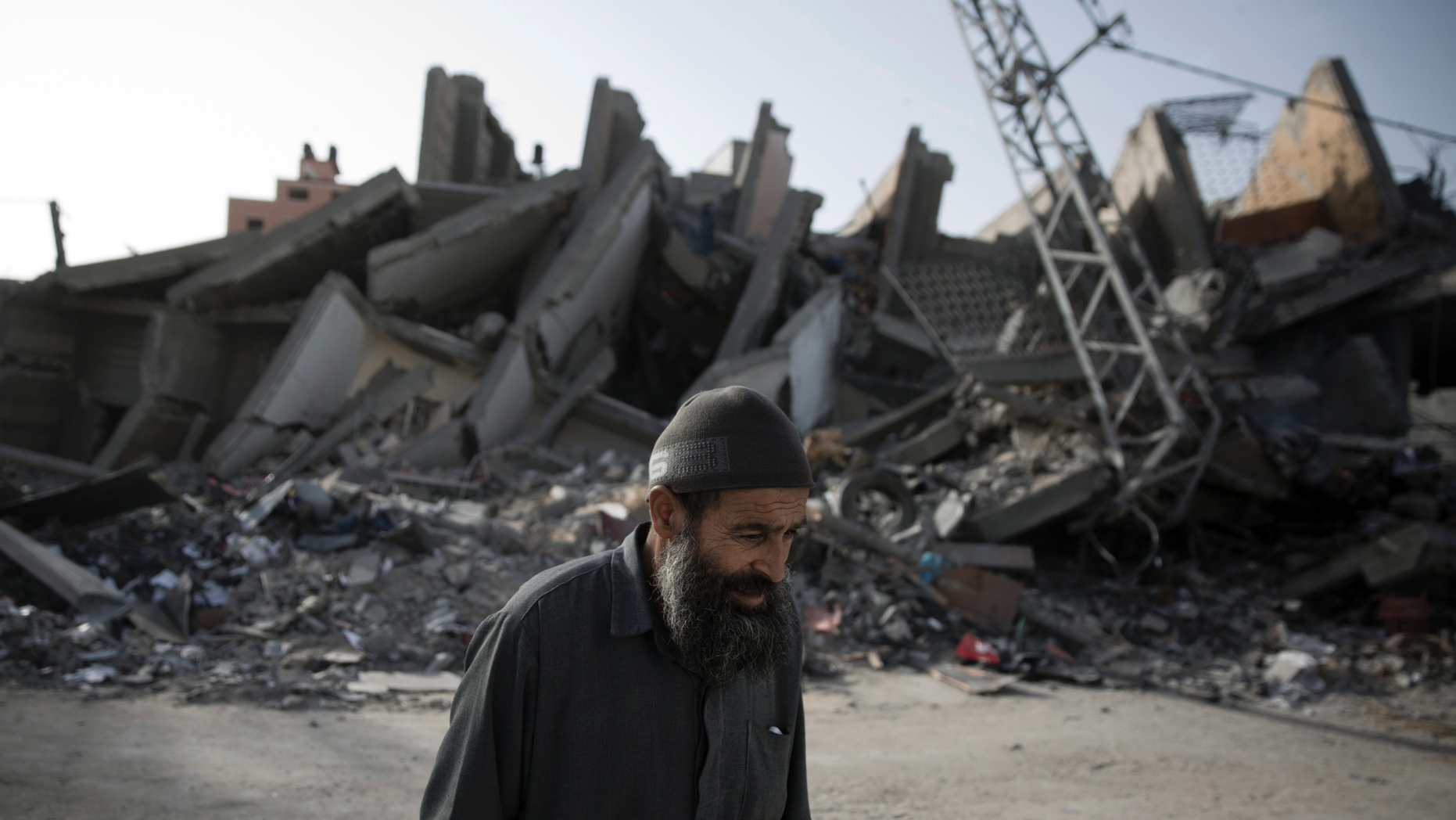 An elderly Palestinian man walks next to the rubble of multi-story building was hit and destroyed on Sunday by Israeli airstrikes, in Gaza City, Monday, May. 6, 2019. The Israeli military has lifted protective restrictions on residents in southern Israel while Gaza's ruling Hamas militant group reported a cease-fire deal had been reached to end the deadliest fighting between the two sides since a 2014 war. (AP Photo/Khalil Hamra)