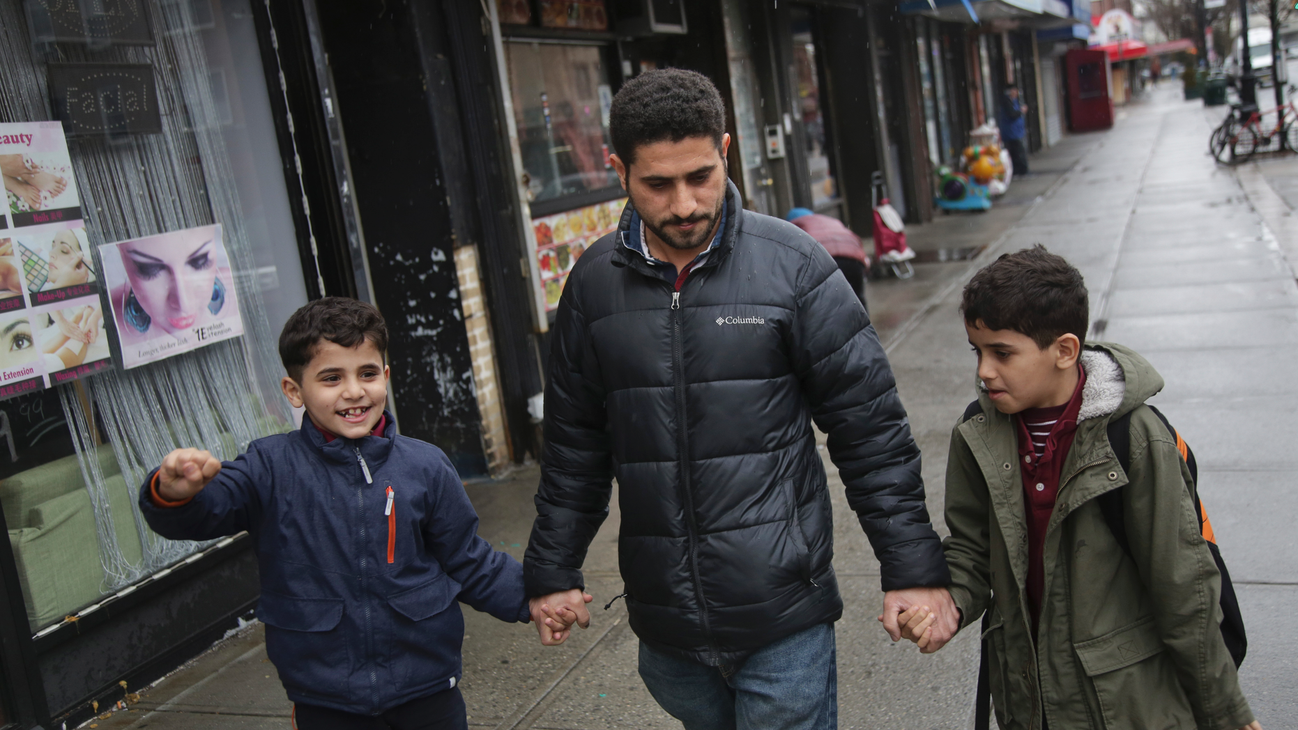 In this March 21, 2019, photo, Sadek Ahmed walks with his sons Adel, 9, right, and Mutaz, 7, after picking them up from school in the Brooklyn borough of New York. Their mother, Amena Abdulkarem, is stuck in Yemen with her two younger sons, the boys’ brothers. Their family’s situation is representative of the toll that the Trump administration’s almost-forgotten travel ban has taken on an untold number of families. (AP Photo/Seth Wenig)