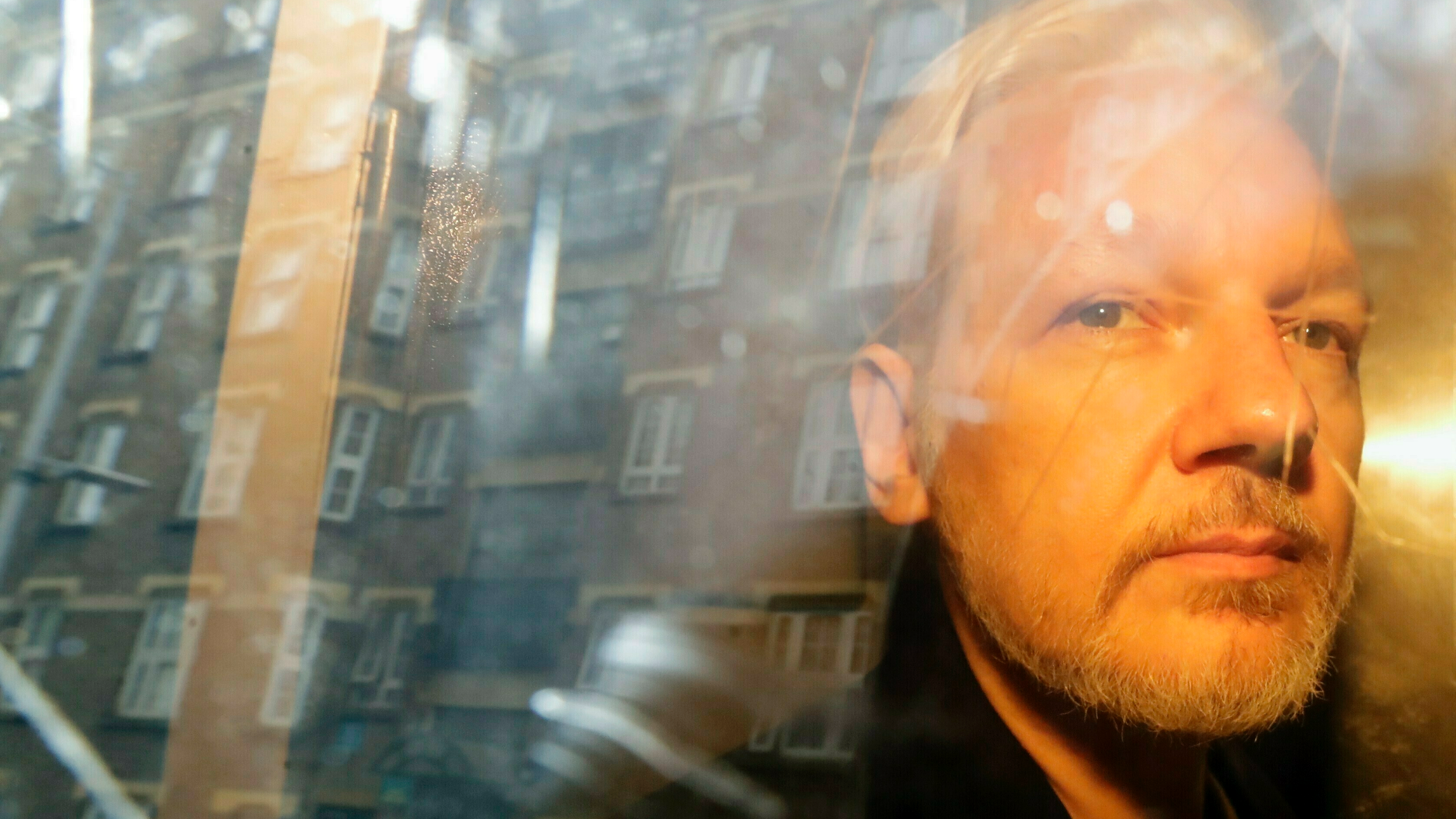 FILE - In this Wednesday May 1, 2019 file photo, buildings are reflected in the window as WikiLeaks founder Julian Assange is taken from court, where he appeared on charges of jumping British bail seven years ago, in London. Swedish prosecutors plan to decide whether they will reopen a rape case against WikiLeaks founder Julian Assange. (AP Photo/Matt Dunham)