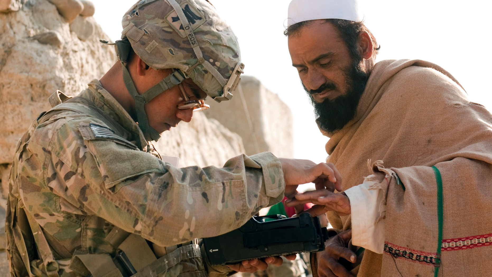 In this Nov. 5, 2012, photo provided by the U.S. Army, U.S. Army Pfc. Mark Domingo, left, takes an Afghan man's fingerprints in the village of Dande Fariqan, in Afghanistan's Khowst Province, as part of the military's effort to gather biometric data on the residents. Domingo, an Army veteran who converted to Islam and discussed launching various terror attacks throughout Southern California, was arrested as he plotted to bomb a white supremacist rally as retribution for the New Zealand mosque attacks, federal prosecutors said Monday, April 29, 2019. (Sgt. Christopher Bonebrake/U.S. Army via AP)