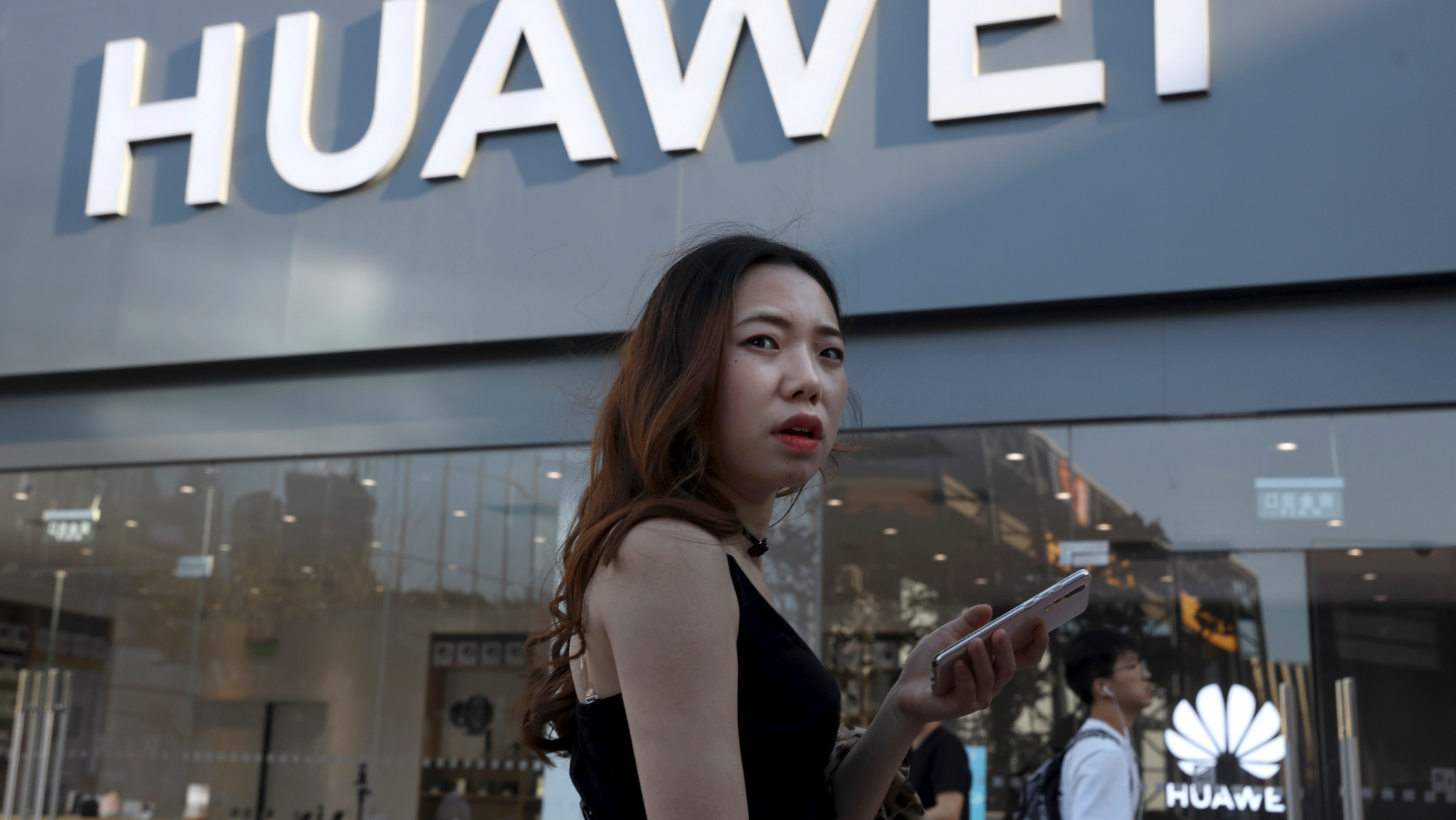 A woman uses a smartphone outside a Huawei store in Beijing Monday, May 20, 2019. Google is assuring users of Huawei smartphones the American company's services still will work on them following U.S. government restrictions on doing business with the Chinese tech giant. (AP Photo/Ng Han Guan)
