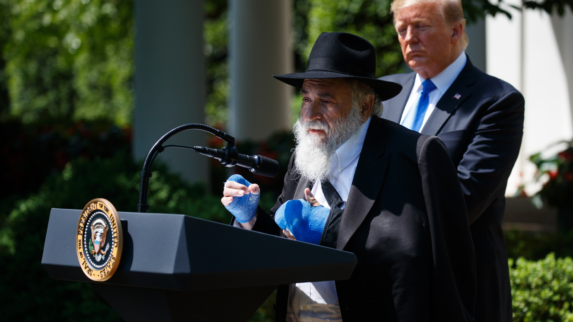 President Donald Trump looks on as Rabbi Yisroel Goldstein, survivor of the Poway, Calif synagogue shooting, speaks during a National Day of Prayer event in the Rose Garden of the White House, Thursday, May 2, 2019, in Washington. (AP Photo/Evan Vucci)