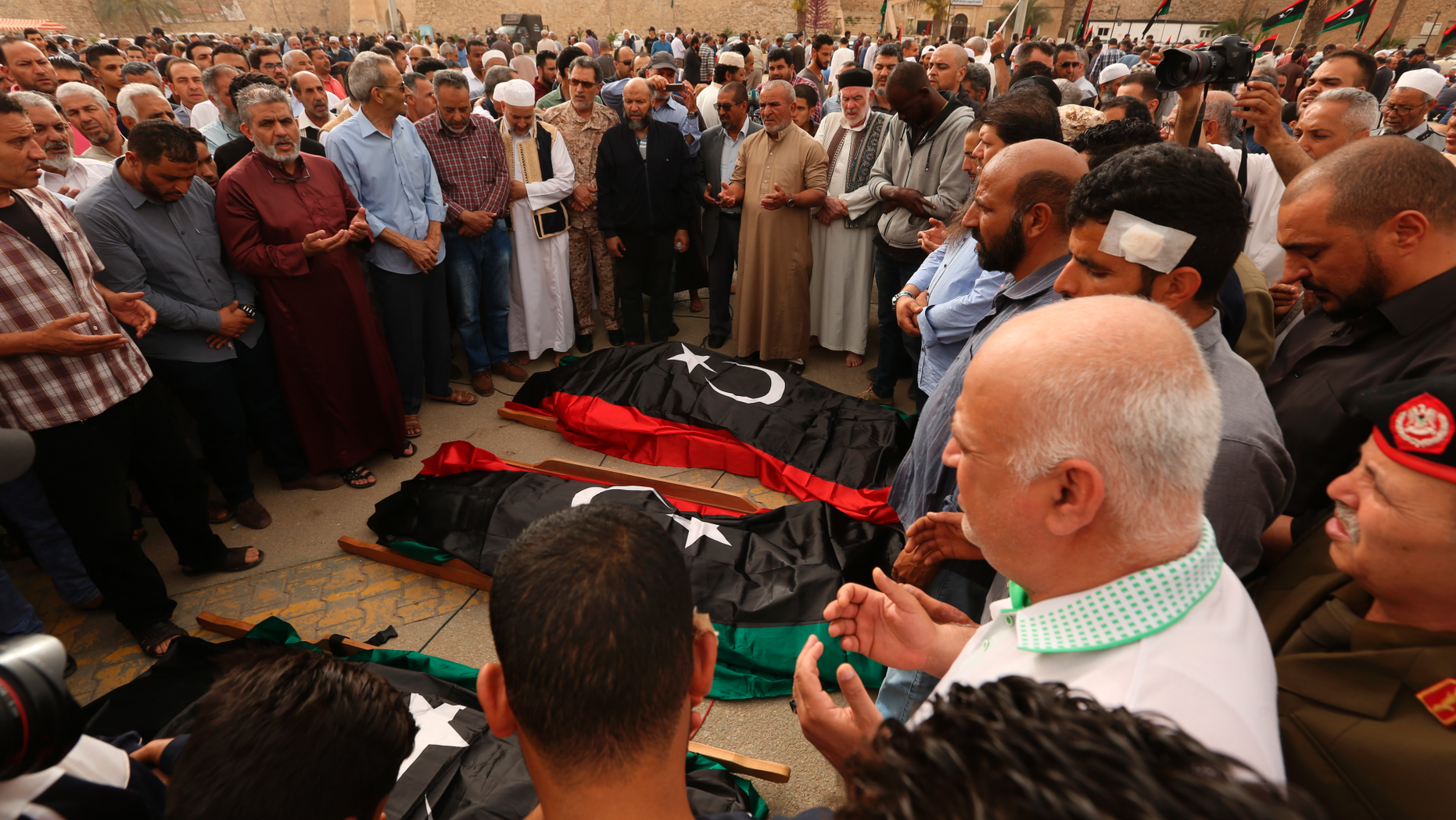 FILE - In this April 24, 2019 file photo, mourners pray for fighters killed in airstrikes by warplanes of Field Marshal Khalifa Hifter's forces, in Tripoli, Libya. After years of assassinations, bombings and militia firefights, Libya’s eastern city of Benghazi finally feels safe again, but the city center lies in ruins, thousands remain displaced, and forces loyal to Hifter, who now controls eastern Libya, have cracked down on dissent. Benghazi offers a glimpse of what may befall the capital, Tripoli, where Hifter’s forces launched an offensive in April against rival militias loosely allied with a weak, U.N.-recognized government. (AP Photo/Hazem Ahmed, File)