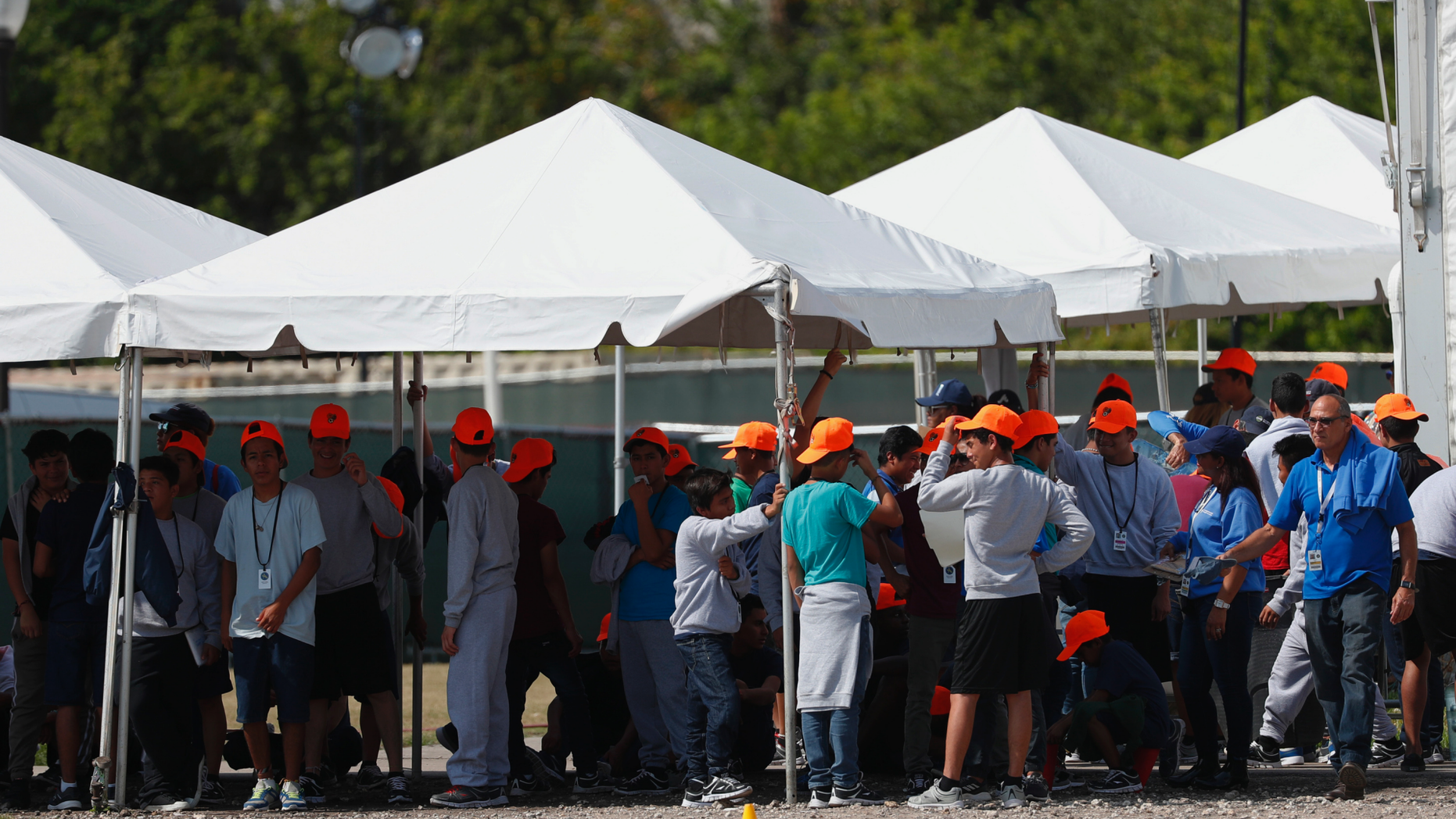 FILE - In this Monday, May 6, 2019 file photo, migrant children stand outside the Homestead Temporary Shelter for Unaccompanied Children in Homestead, Fla. The U.S. government is providing long-distance video counseling to teens housed at the country's largest migrant detention center as officials struggle to accommodate increasing numbers of minors illegally crossing the U.S.-Mexico border. Some mental health experts and human rights advocates say that may not be the best way to help young people coping with trauma. (AP Photo/Wilfredo Lee, File)