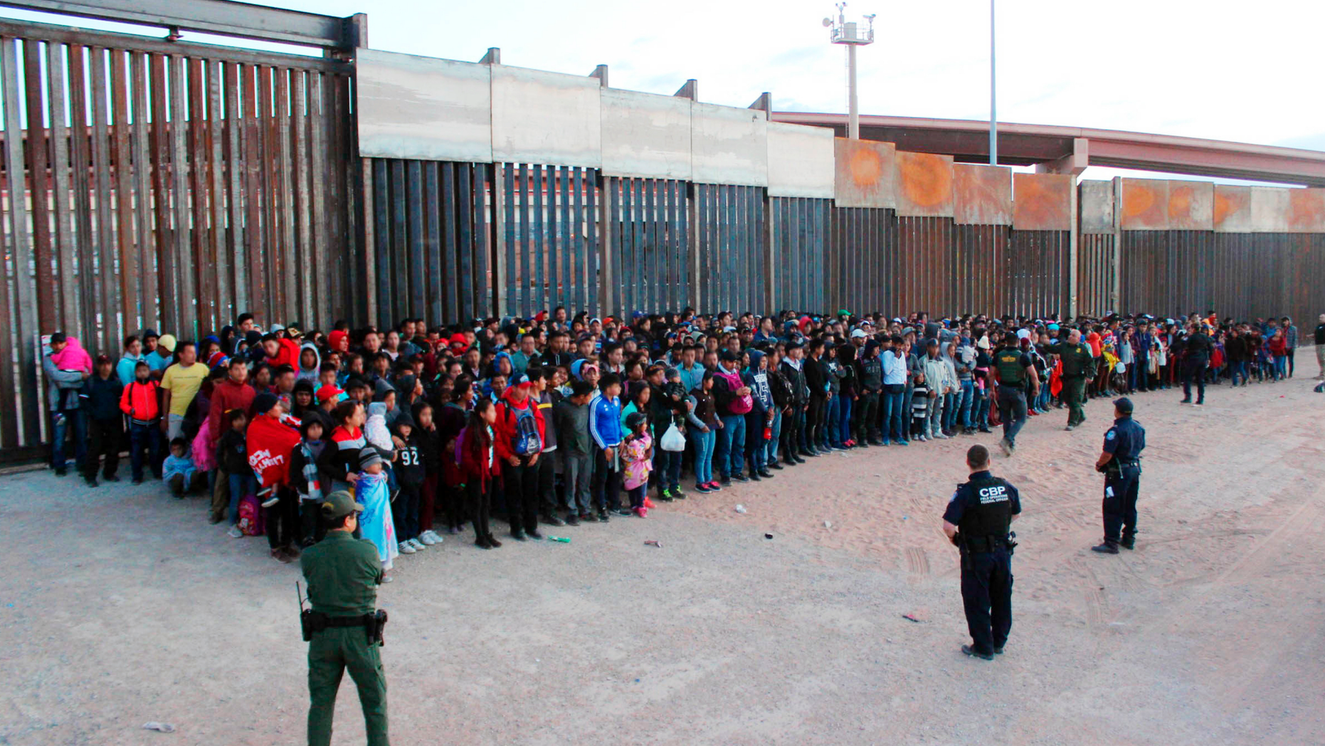 This May 29, 2019 photo released by U.S. Customs and Border Protection (CBP) shows some of 1,036 migrants who crossed the U.S.-Mexico border in El Paso, Texas, the largest that the Border Patrol says it has ever encountered. Video shows them going under a chain-link fence to the U.S., where they waited for agents to come. The Border Patrol has encountered 180 groups of more than 100 people since October, compared to 13 during the previous 12-month period and two the year before. (U.S. Customs and Border Protection via AP)