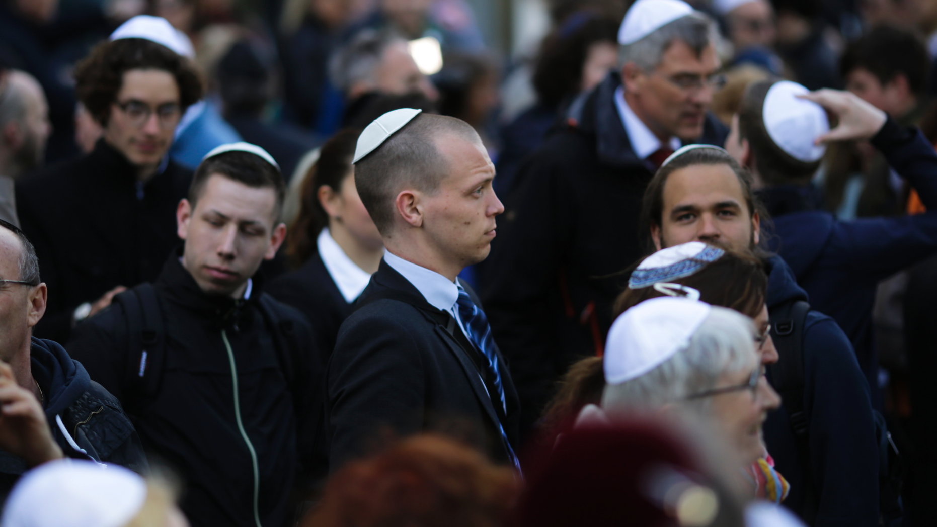 In this Wednesday, April 25, 2018 file photo, people wear Jewish skullcaps, as they attend a demonstration against an anti-Semitic attack in Berlin. Chancellor Angela Merkel's spokesman has stressed Germany's responsibility to ensure security for all Jews wearing skullcaps anywhere in the country without having to fear an anti-Semitic attack. (AP Photo/Markus Schreiber)