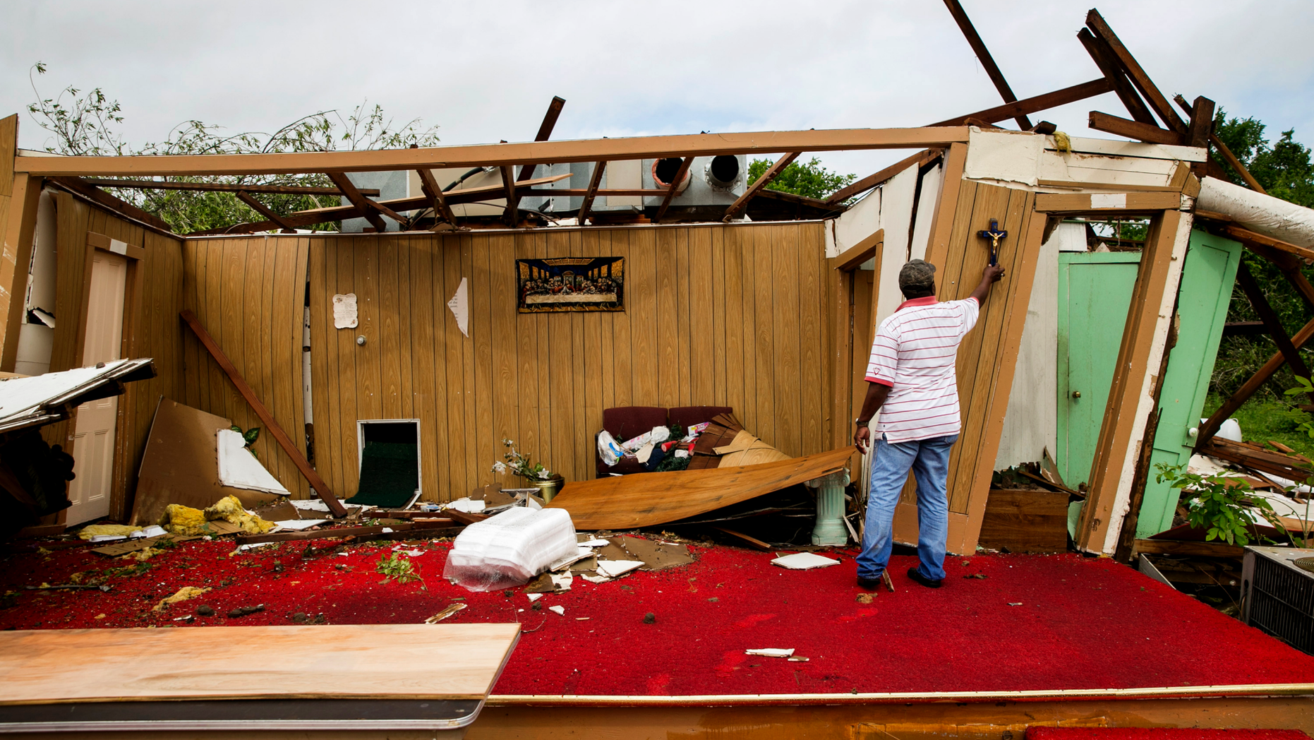 Melvin Jackson touches a cross that remained on the wall after a tornado destroyed Mt. Zion Baptist Church, a historic African American church, in La Grange, Texas, on Friday May 3, 2019. (Jay Janner/Austin American-Statesman via AP)