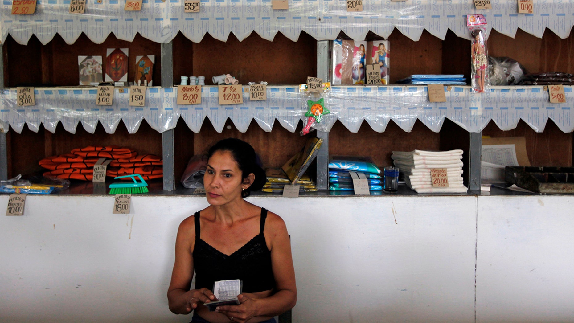 A worker holds a rationing booklet at a government-run food store called "Bodega" in Sagua La Grande, Villaclara Province, central Cuba November 8, 2009. REUTERS/Desmond Boylan (CUBA SOCIETY FOOD)