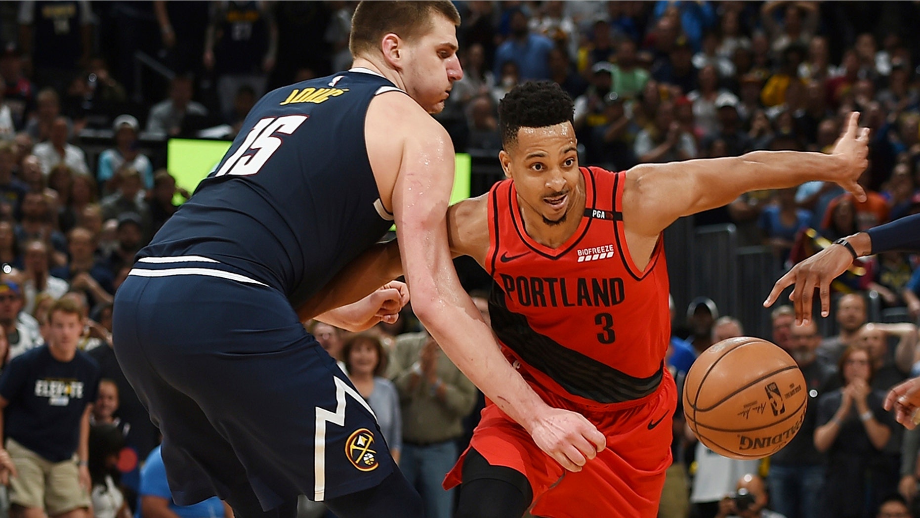 Portland Trail Blazers guard CJ McCollum, right, pursues the ball with Denver Nuggets center Nikola Jokic in the second half of Game 7 of an NBA basketball second-round playoff series Sunday, May 12, 2019, in Denver. (AP Photo/David Zalubowski)