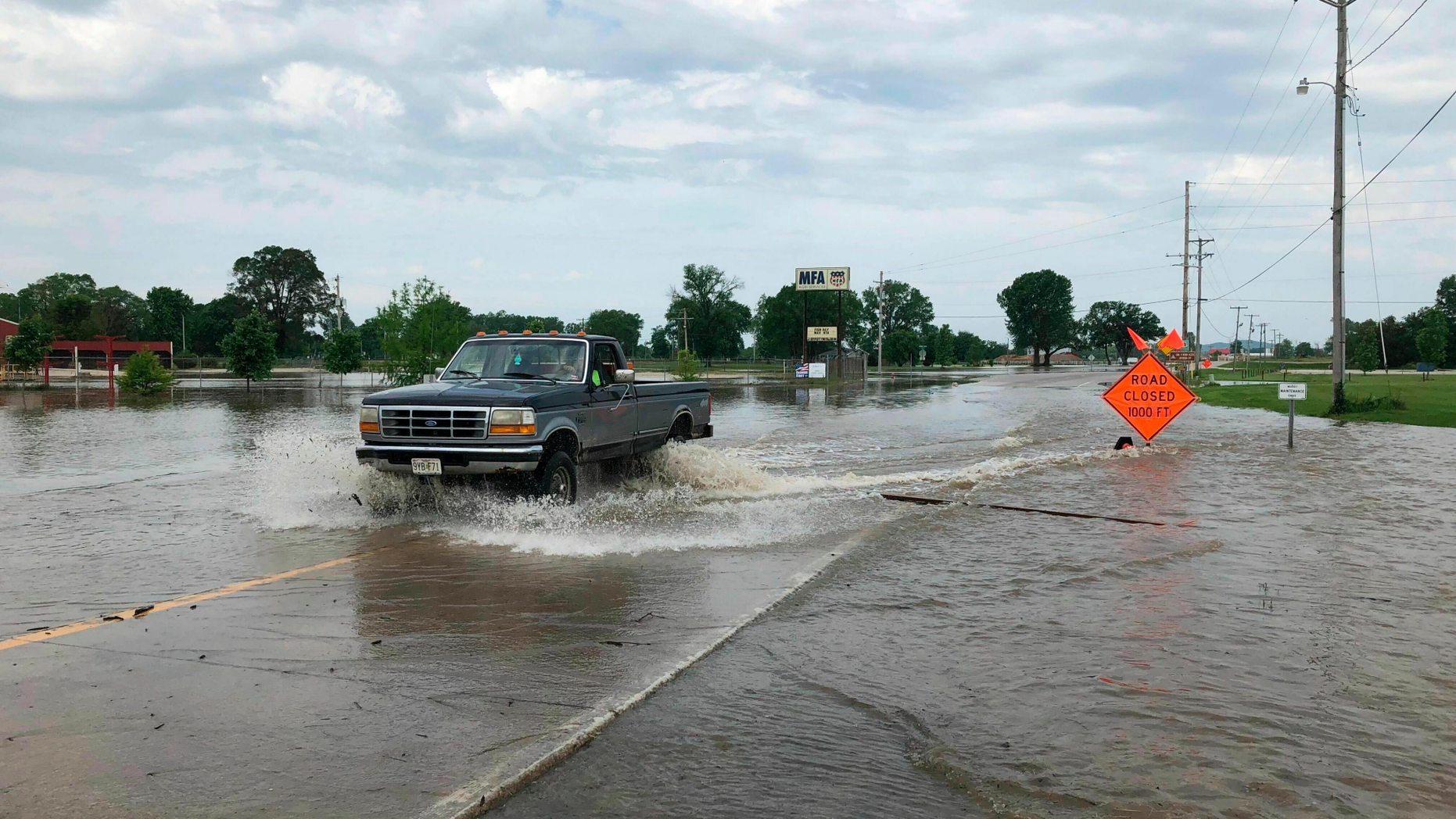 A pickup truck evacuates from an area in north Jefferson City Missouri as floodwaters from the Missouri River rise over the road on Friday, May 24, 2019. The flooding come as residents are still cleaning up from a powerful tornado that hit the state's capital city on May 22. (AP Photo/David A. Lieb)