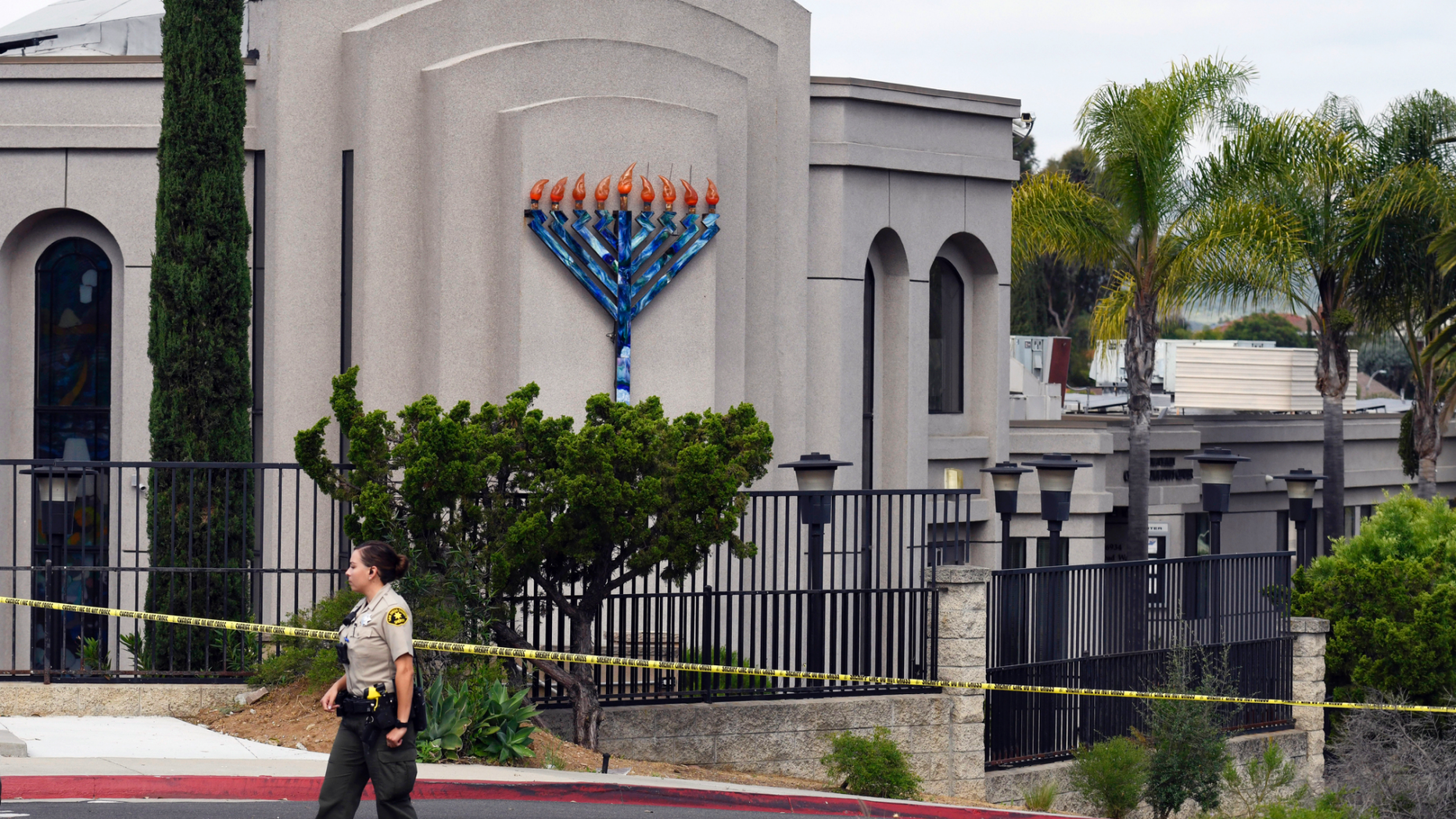 FILE - In this Sunday, April 28, 2019 file photo, a San Diego county sheriff's deputy stands in front of the Poway Chabad Synagogue in Poway, Calif. The gunman who attacked the synagogue last week fired his semi-automatic rifle at Passover worshippers after walking through the front entrance that synagogue leaders identified last year as needing improved security. The synagogue applied for a federal grant to better protect that area. The money, $150,000, was approved in September but only arrived in late March. "Obviously we did not have a chance to start using the funds yet," Rabbi Scimcha Backman told The Associated Press. (AP Photo/Denis Poroy, File)