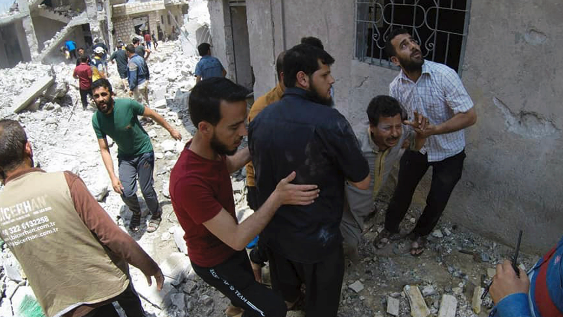 This photo posted and provided by the Syrian Civil Defense White Helmets, which has been authenticated based on its contents and other AP reporting, shows Syrians gathering at the scene where an airstrike by Syrian government forces hit the town of Jabal al-Zawiya in Idlib province, Syria, Saturday, June 15, 2019. Syrian opposition activists say government airstrikes on rebel-held areas in northwestern Syrian and intense fighting claimed the lives dozens of people. (Syrian Civil Defense White Helmets via AP)