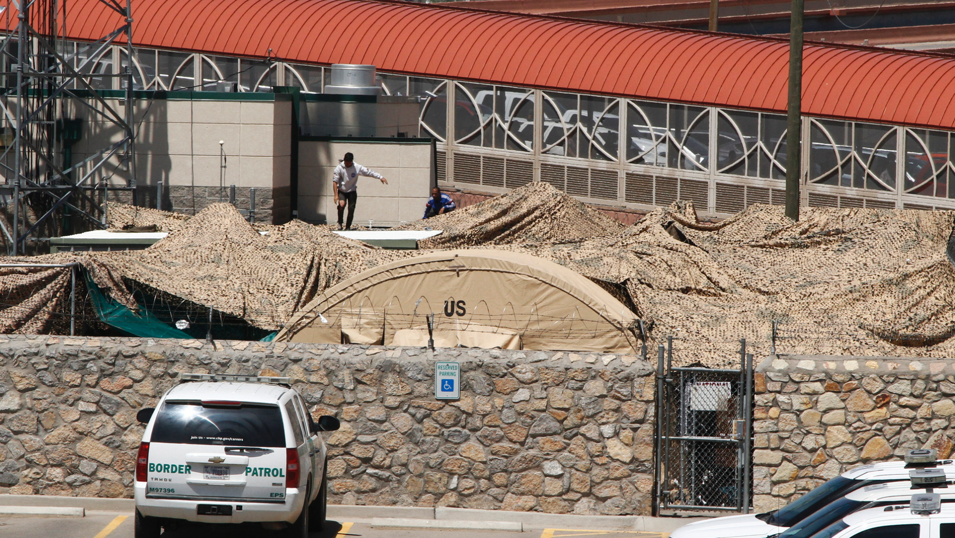 In this June 7, 2019, photo, migrants adjust a shade canopy over an outdoor encampment where they're waiting to be processed by immigration in El Paso, Texas. The Trump administration is facing growing complaints from migrants about severe overcrowding, meager food and other hardships at border holding centers like this one. [AP Photo/Cedar Attanasio)