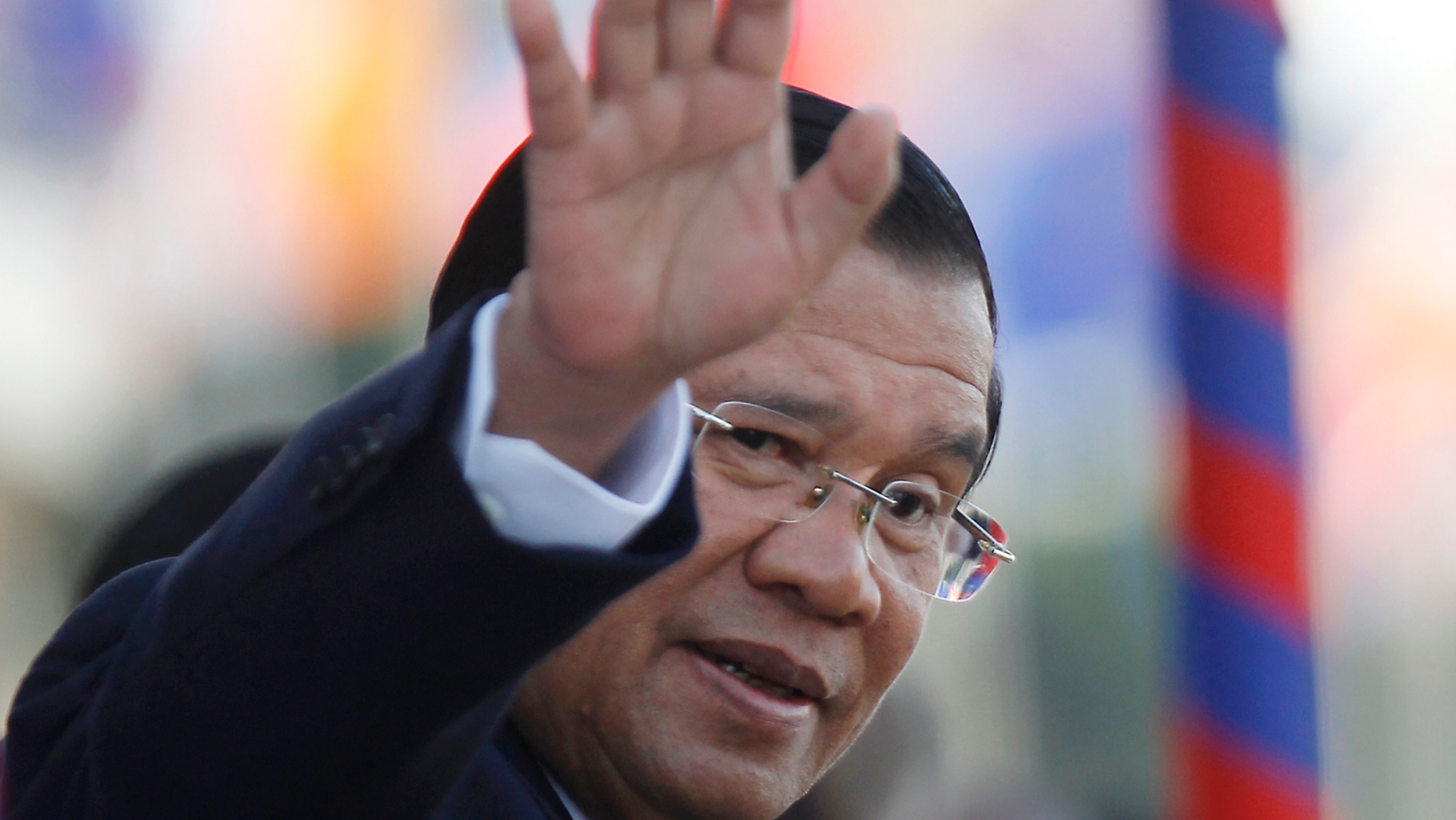 FILE - In this Nov. 21, 2018, file photo, Cambodia's Prime Minister Hun Sen waves as he watches boat races during the water festival in Phnom Penh, Cambodia. The bitter decadeslong rivalry between Hun Sen, Cambodia's strongman leader, and Sam Rainsy, the self-exiled chief political rival and critic, has sometimes played out in deadly violence. But on Sunday, soup rather than blood was likely to be spilled. (AP Photo/Heng Sinith, File)