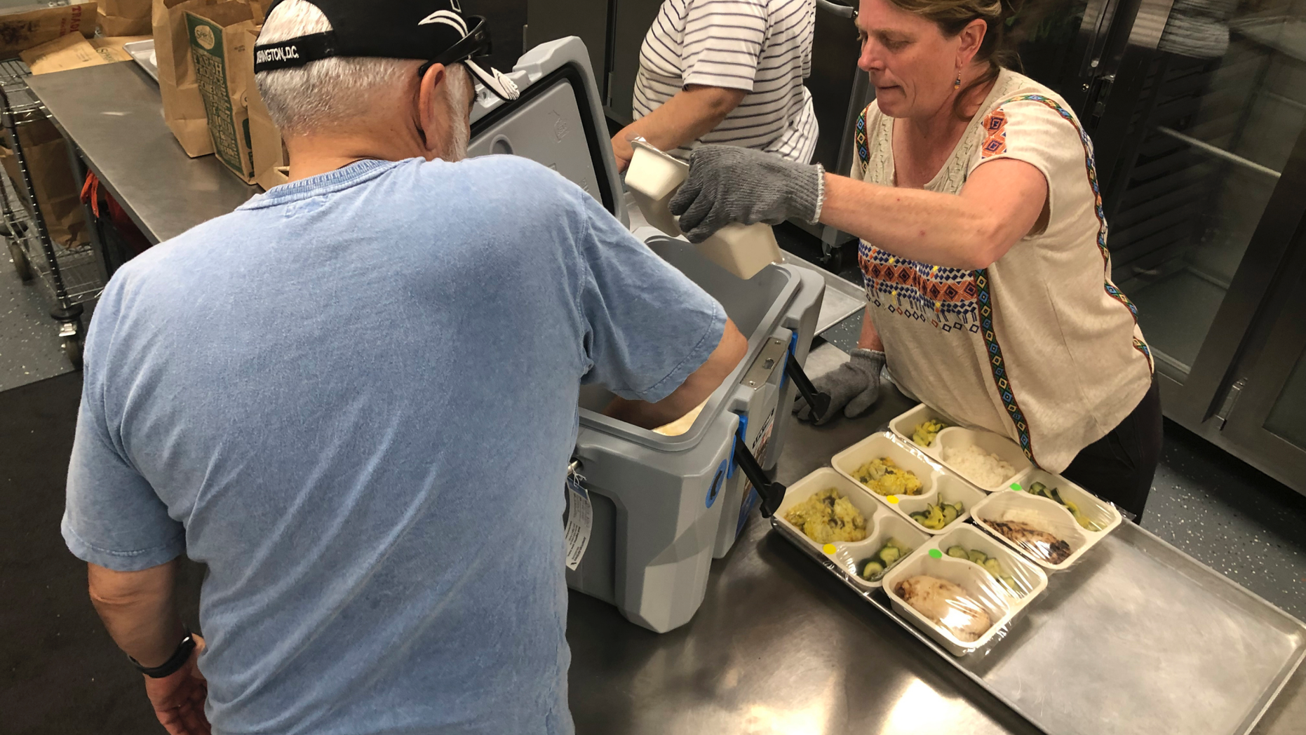 In this photo taken Friday, June 14, 2019, volunteers including Shelley Winship and retired accountant Ralph Nava, left, pick up food packages to deliver to homebound families and dependent children in Santa Fe, N.M., at the headquarters for Kitchen Angels. An annual report on childhood well-being from the Annie E. Casey Foundation ranks New Mexico last among 50 states that includes measures of poverty, health care, education and family support. The number of children living in poverty has swelled over the past three decades in fast-growing, ethnically diverse states such as Texas, Arizona and Nevada as the nation's population center shifts south and west. (AP Photo/Morgan Lee)