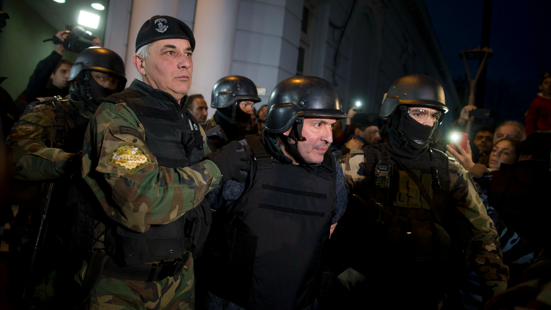 FILE - In this June 14, 2016 file photo, former Public Works Secretary Jose Lopez, center, is escort by police outside the a police station in the outskirts of Buenos Aires, Argentina. A court in Argentina sentenced Lopez on Wednesday, June 12, 2019, to 6 years in prison for illicit enrichment after he tried to hide millions of dollars in cash at a convent. (AP Photo/Natacha Pisarenko, File)