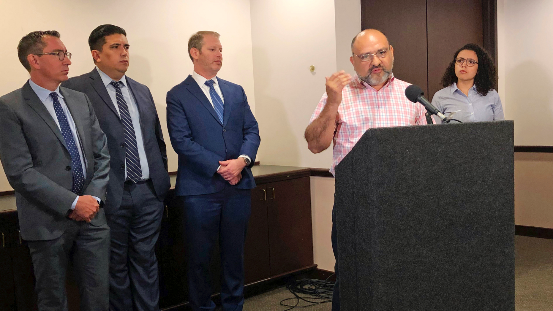 Pastor Angel Campos of Iglesia Monte Vista in Phoenix, at podium, talks Tuesday, June 4, 2019 about feeling afraid and harassed by two anti-immigrant groups who have protested at his church over its aiding immigrant families who have recently arrived at the southern border. The Southern Poverty Law Center is suing the groups to try to stop them. (AP Photo/Astrid Galvan)