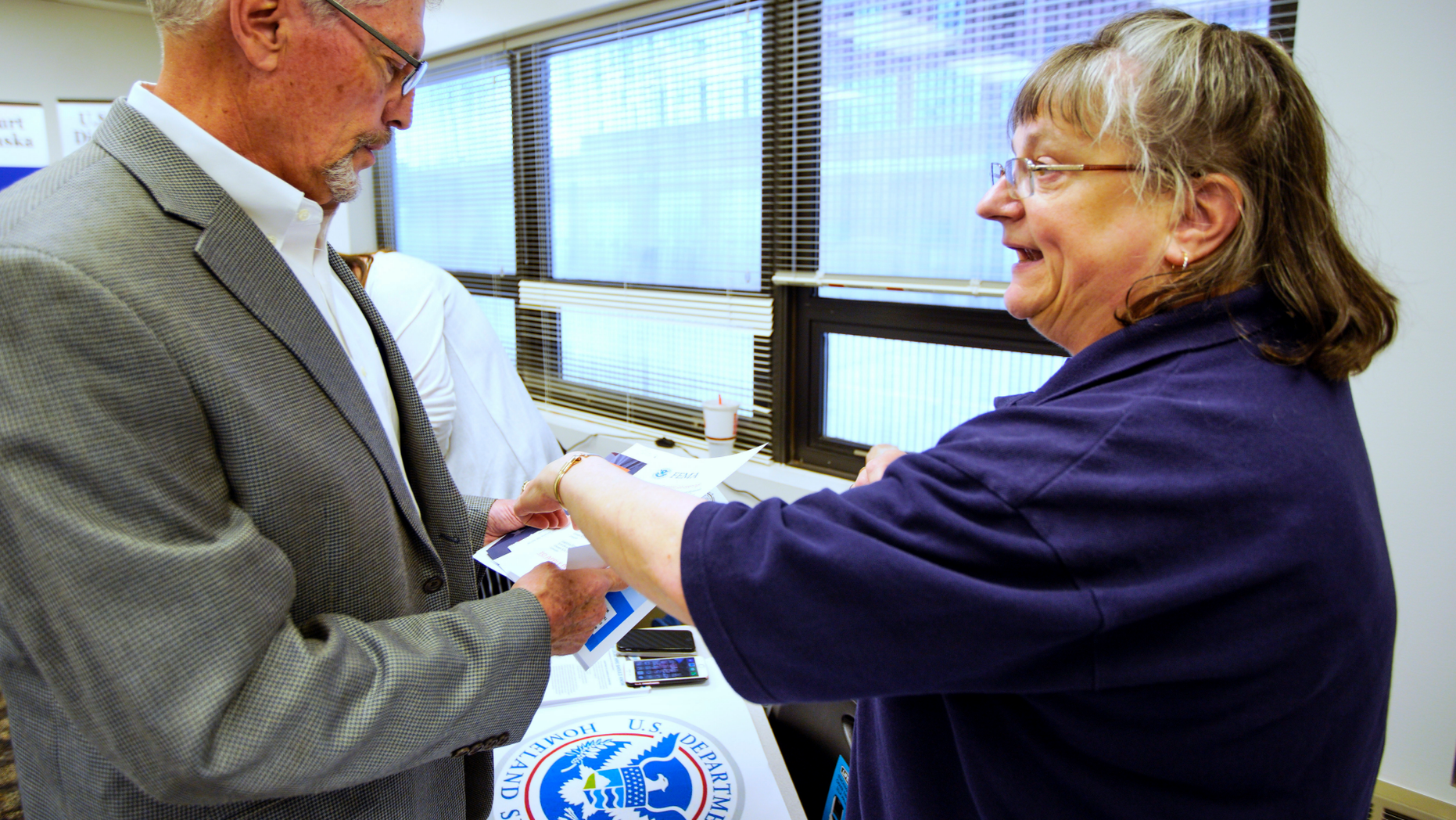 In this April 25, 2019 photo, FEMA representative Kristina Pooler, right, talks to Ned Holmes, National Guard Employment Support specialist, about available FEMA jobs, at a job fair in Lincoln, Neb. With federal disaster recovery staffers scrambling to meet needs amid floods, hurricanes and fires, they are now dealing with another issue _ historically low unemployment that's hampering their efforts to hire workers to help with the calamities. (AP Photo/Nati Harnik)