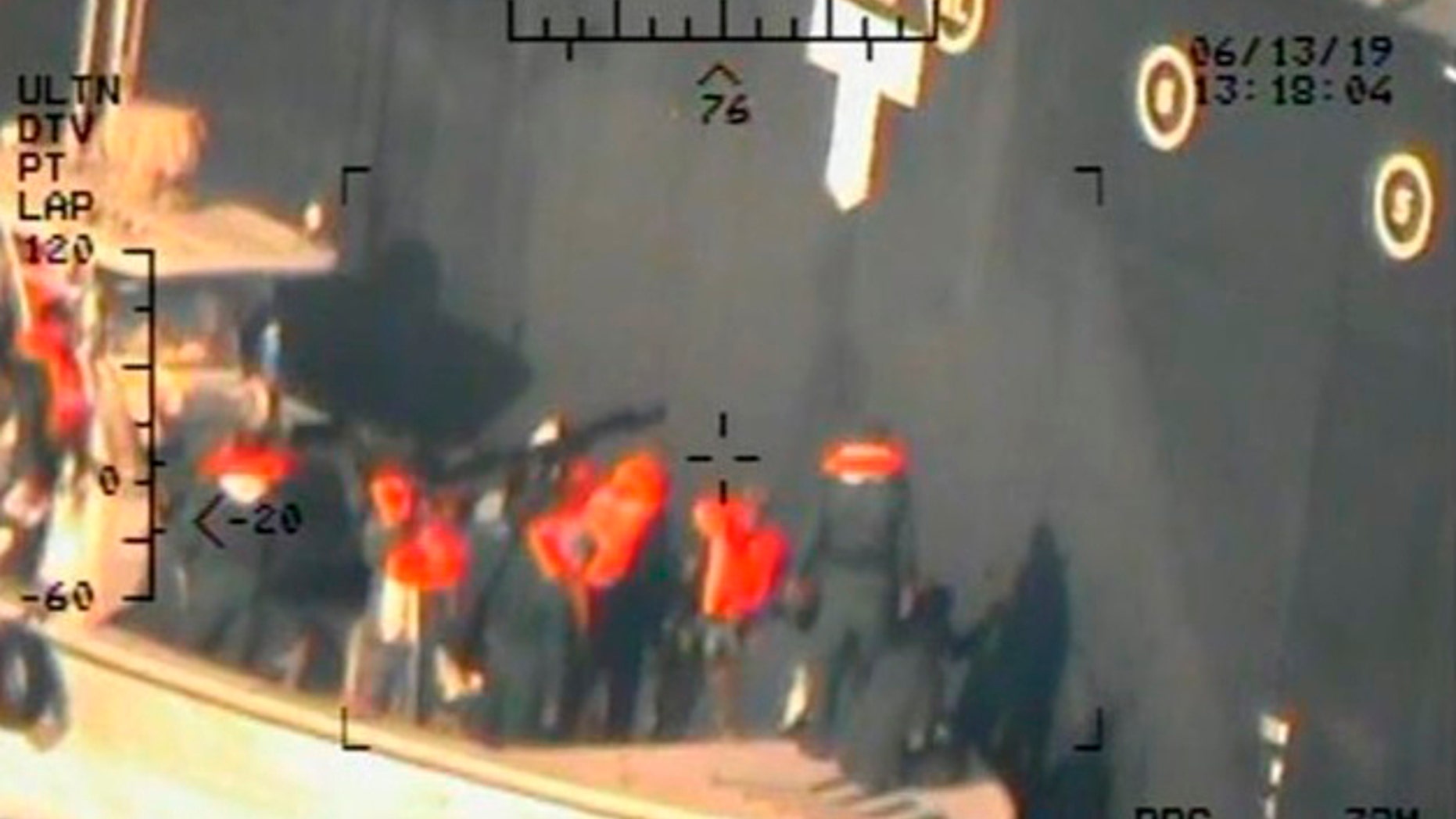 This image released by the U.S. Department of Defense on Monday, June 17, 2019, and taken from a U.S. Navy helicopter, shows what the Navy says are members of the Islamic Revolutionary Guard Corps Navy removing an unexploded limpet mine from the M/T Kokuka Courageous. (U.S. Department of Defense via AP)