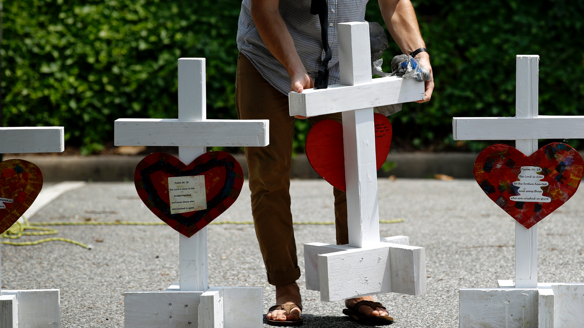 FILE - In this June 2, 2019, file photo, a volunteer prepares to place crosses for victims of a mass shooting at a municipal building in Virginia Beach, Va., at a nearby makeshift memorial. Police responding to the deadly mass shooting were unable to confront the gunman at one point because they didn’t have the key cards needed to open doors on the second floor. Whether the delay contributed to the death toll is unclear, but the episode illustrated how door-lock technology that is supposed to protect people can hamper police and rescue workers in an emergency. (AP Photo/Patrick Semansky, File)