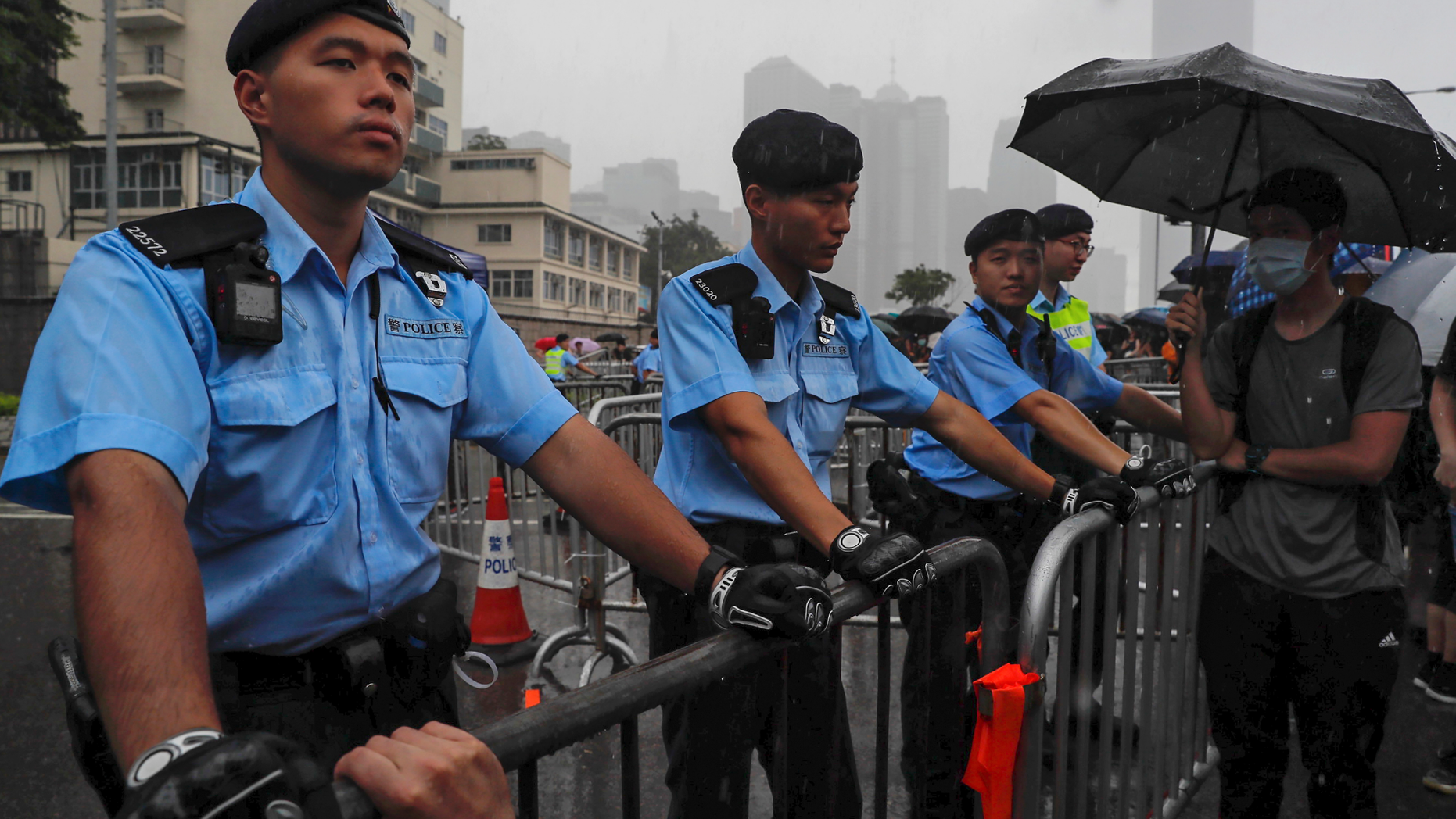Policemen stand guard in the rain as protesters gather near the Legislative Council continuing protest against the unpopular extradition bill in Hong Kong, Monday, June 17, 2019. A member of Hong Kong's Executive Council says the city's leader plans to apologize again over her handling of a highly unpopular extradition bill. (AP Photo/Kin Cheung)