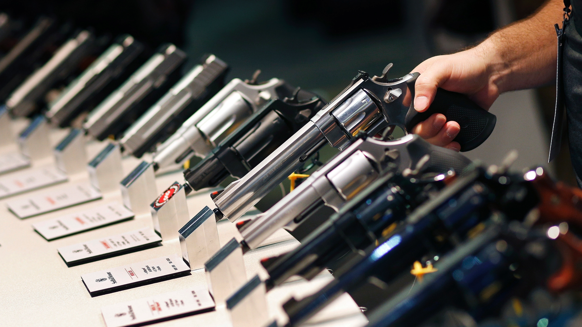 FILE - In this Jan. 19, 2016 file photo, handguns are displayed at the Smith & Wesson booth at the Shooting, Hunting and Outdoor Trade Show in Las Vegas. Two former trade show workers have pleaded guilty to federal firearms charges following the theft of weapons from the U.S. gun industry's biggest annual convention, Thursday, June 13, 2019. (AP Photo/John Locher, File)