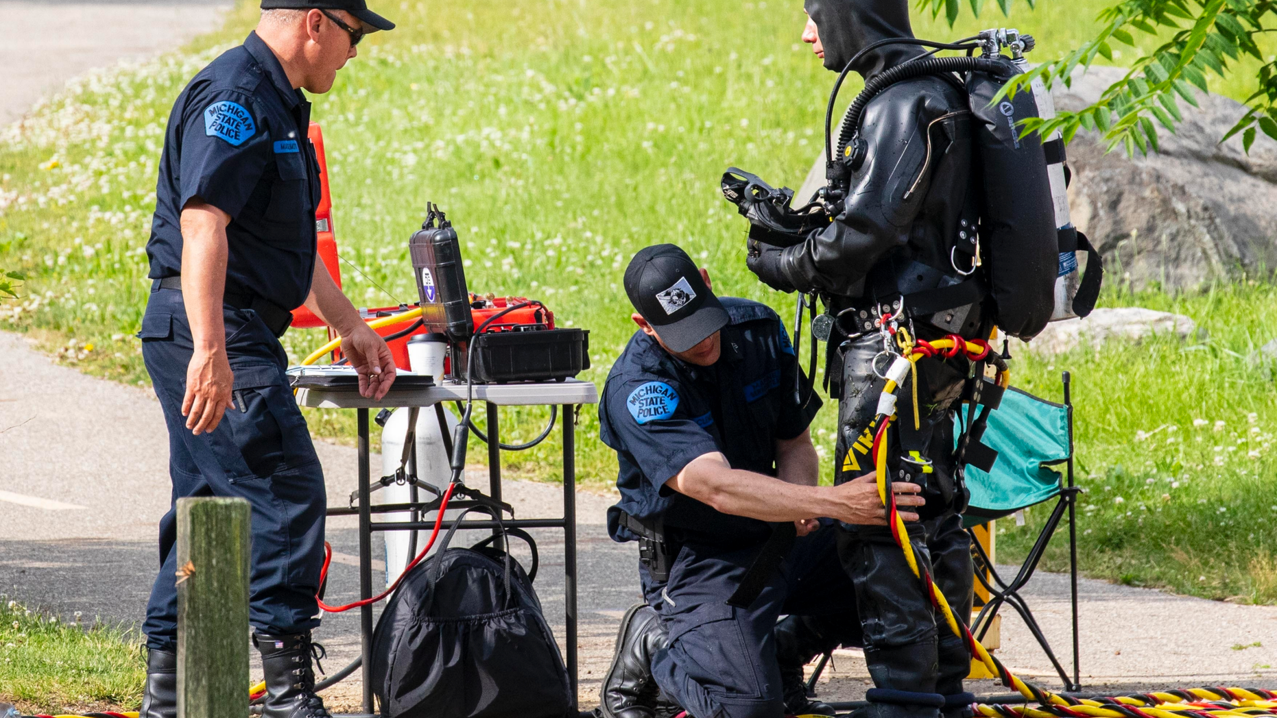 Police search the Kalamazoo River near Verburg Park, Tuesday, June 18, 2019, after finding the bodies of a mother and child inside a submerged vehicle, in Kalamazoo, Mich. Police believe a second child, who is missing, may also have been inside the vehicle when it entered the water late Monday evening. (Joel Bissell/Kalamazoo Gazette via AP)