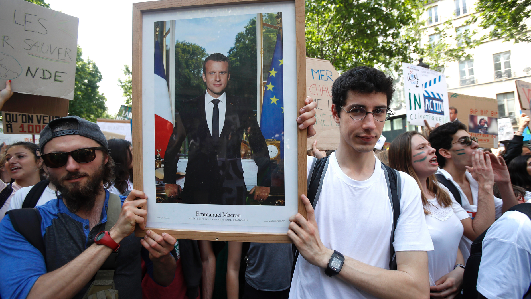 FILE - In this photo taken on Friday May 24, 2019, youths hold the official portrait of French President Emmanuel Macron during a climate march in Paris.Six French activists were convicted Wednesday June 12, 2019 for theft after taking down an official portrait of President Emmanuel Macron to protest his climate change policies they consider as not strong enough. (AP Photo/Michel Euler, File)
