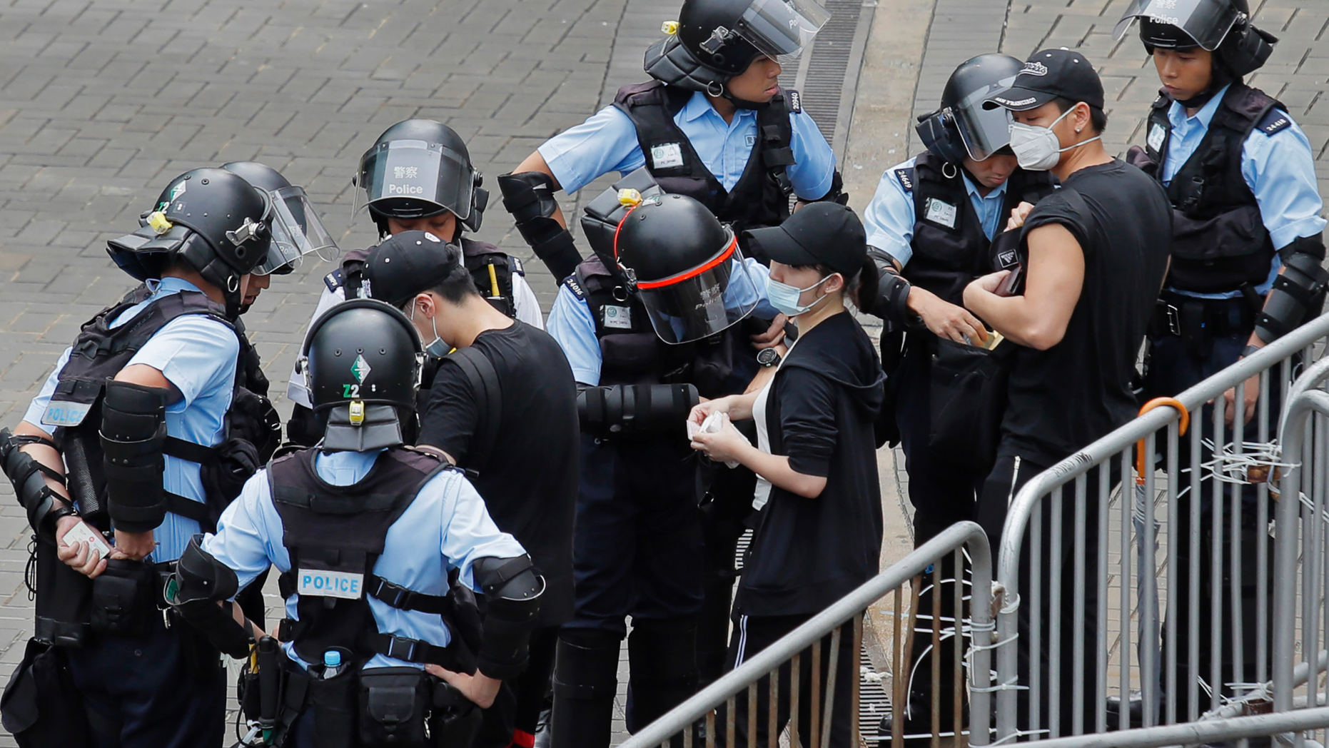 Riot police check the bags of protesters outside the Legislative Council in Hong Kong, Thursday, June 13, 2019. After days of silence, Chinese state media is characterizing the largely peaceful demonstrations in Hong Kong as a "riot" and accusing protesters of "violent acts." (AP Photo/Kin Cheung)