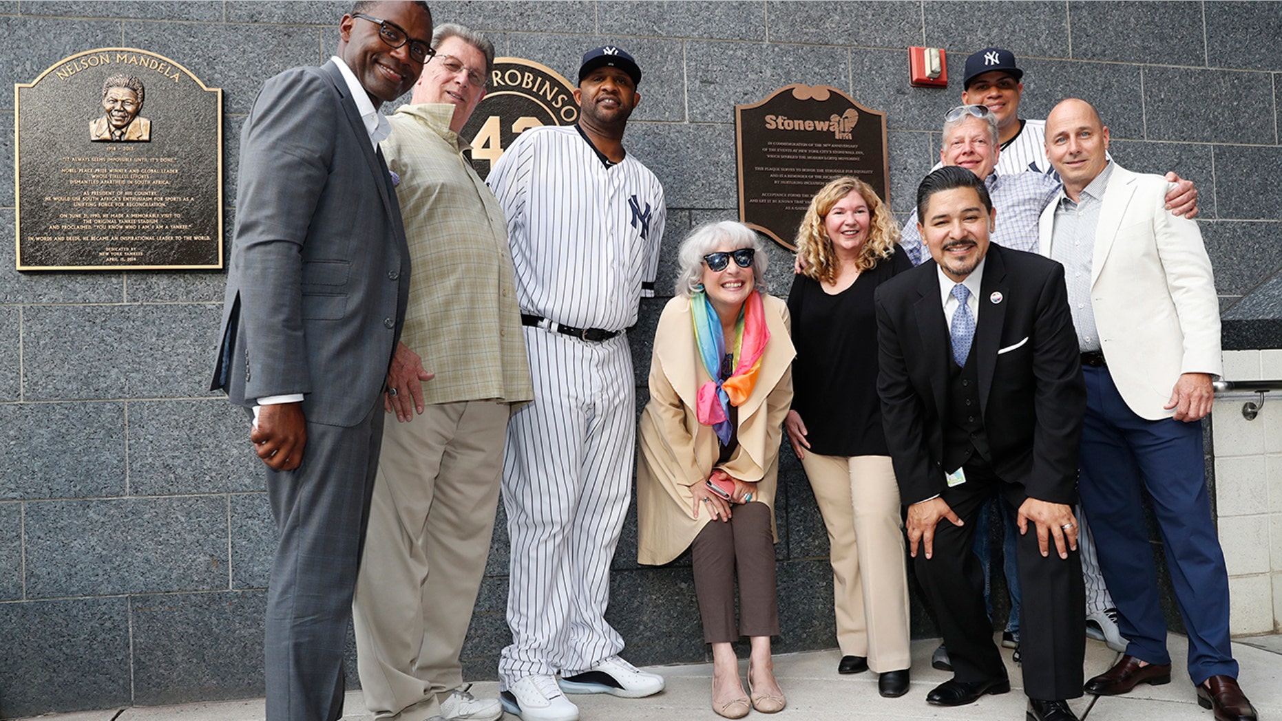 Representatives of the the Stonewall Inn and the New York Yankees, including pitcher CC Sabathia, third from left; relief pitcher Dellin Betances, second from right; assistant general manager Jean Afterman, center; and general manager Brian Cashman, right, honor the 50th anniversary of the Stonewall Inn Uprising after the Yankees unveiled a plaque in Monument Park before a baseball game Tuesday, June 25, 2019, in New York. (AP Photo/Kathy Willens)