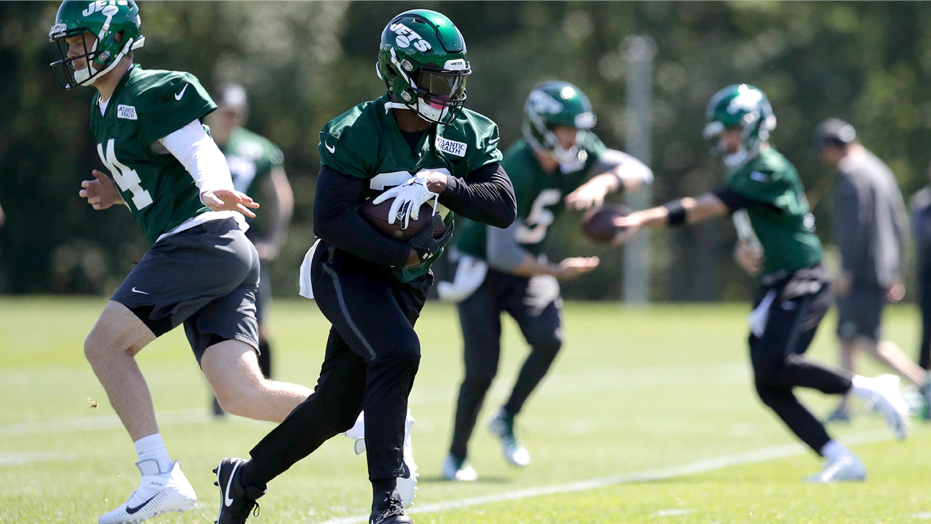 New York Jets quarterback Sam Darnold, left, hands off to running back Le'Veon Bell while running a drill at the team's NFL football training facility in Florham Park, N.J., Tuesday, June 4, 2019. (AP Photo/Julio Cortez)