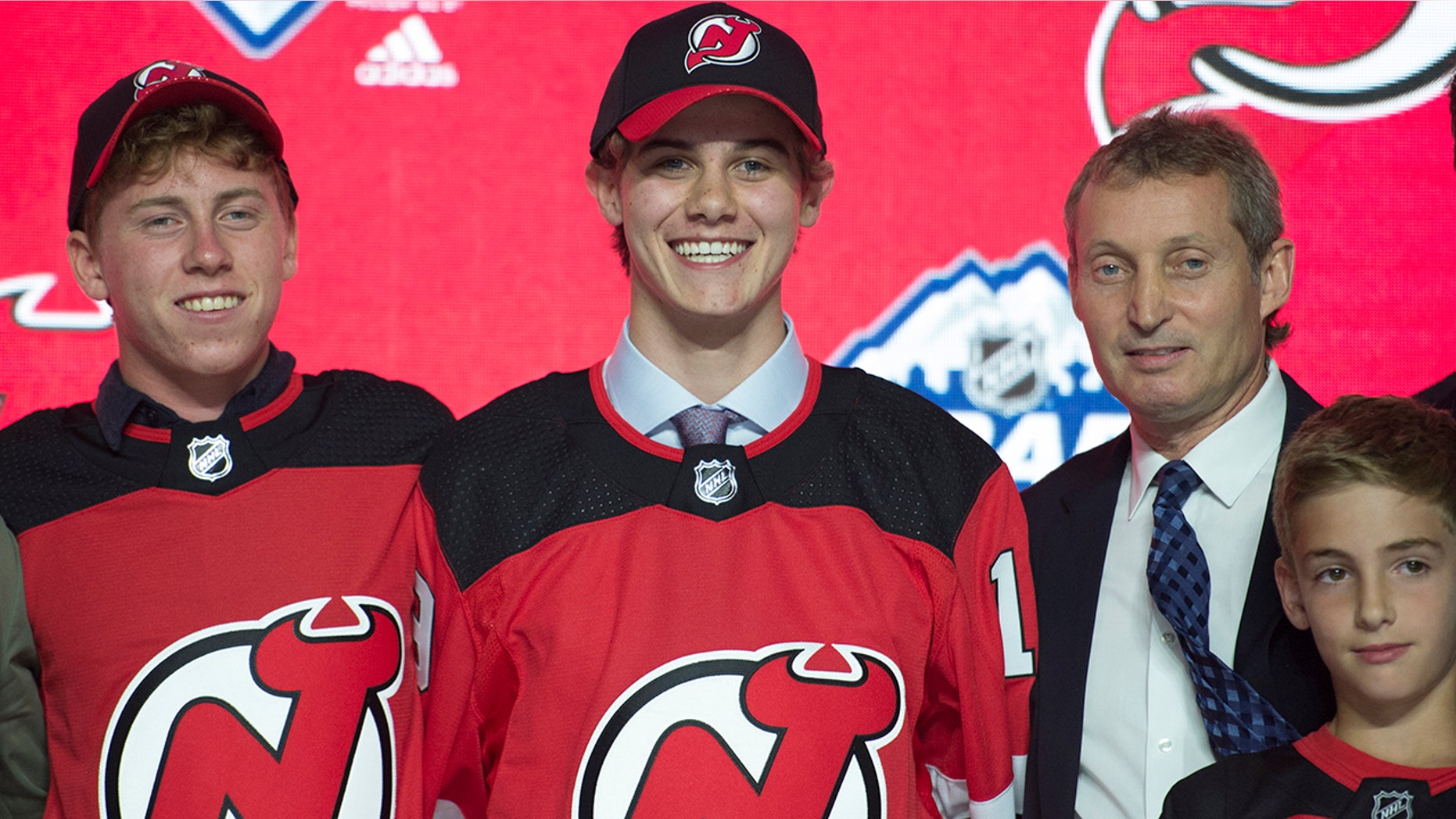Jack Hughes, center, poses for photos after being selected by the New Jersey Devils with the first pick in the NHL hockey draft in Vancouver, British Columbia, Friday, June, 21, 2019. (Jonathan Hayward/The Canadian Press via AP)