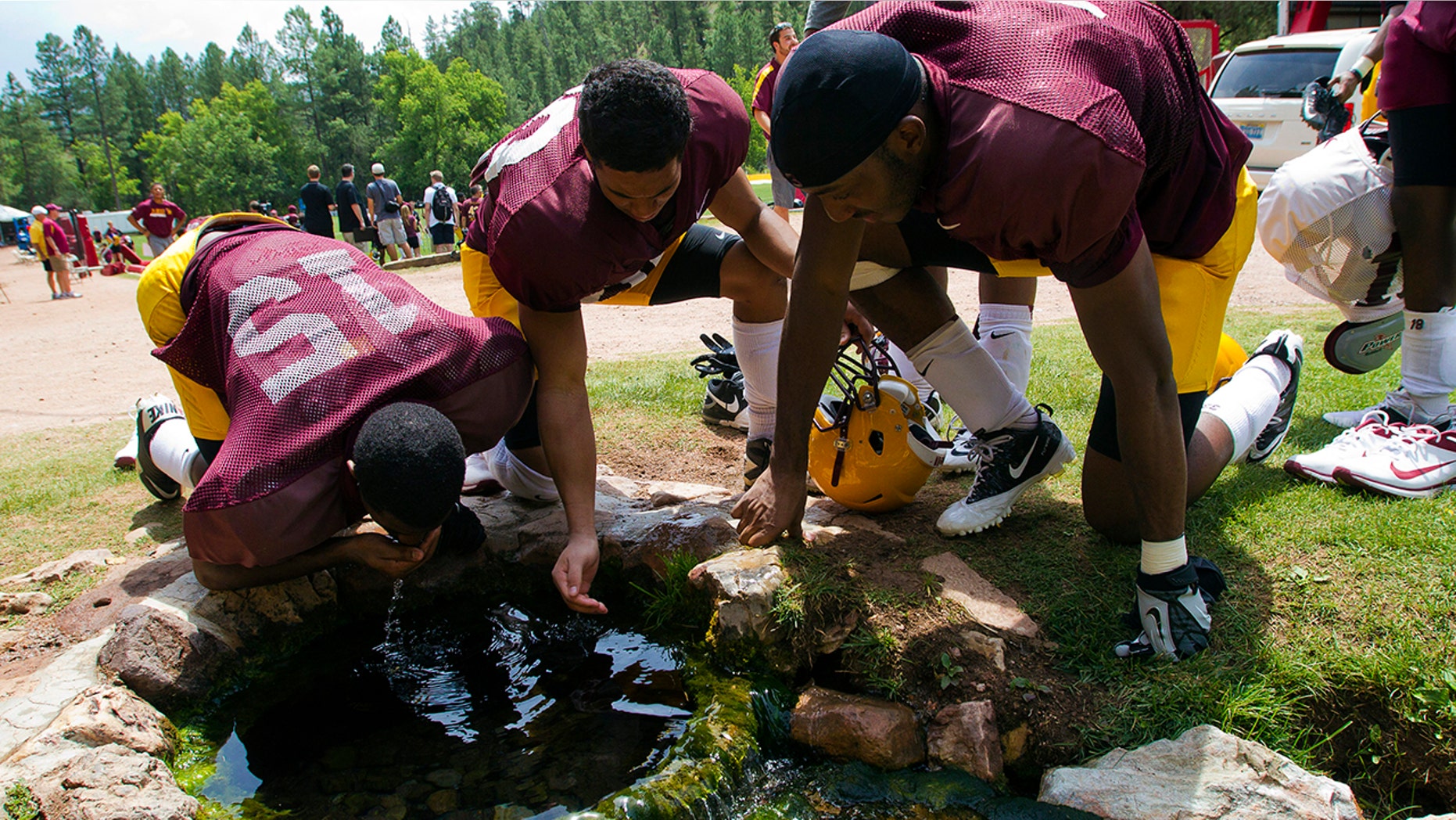 FILE - In this Aug. 15, 2012, file photo, Arizona State wide receivers Rashad Ross, left, JJ Holliday, center, and Alonzo Agwuenu drink water from a spring after NCAA college football practice at Camp Tontozona in Kohls Ranch, Ariz. (Michael Chow/The Arizona Republic via AP, File)