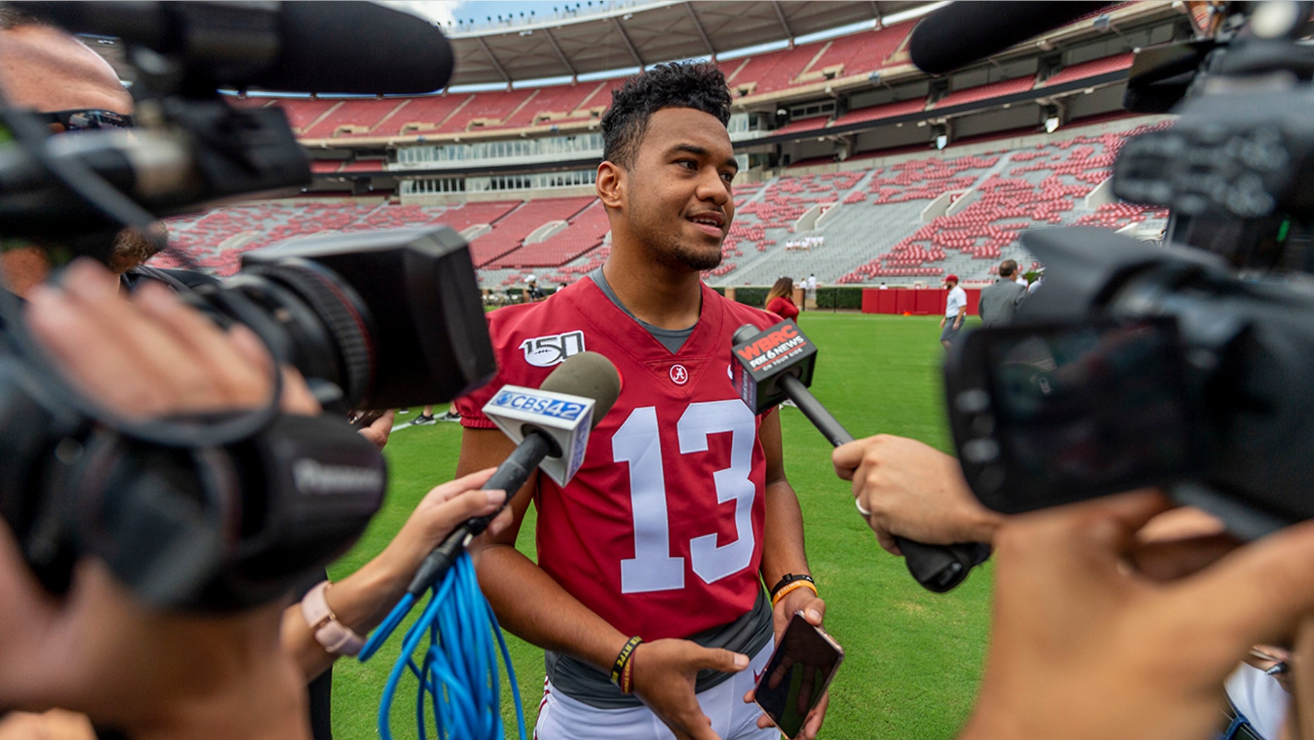 FILE - In this Aug. 3, 2019, file photo, Alabama quarterback Tua Tagovailoa (13) talks with the media prior to Alabama's fall camp fan-day college football scrimmage, in Tuscaloosa, Ala. Two constants remain at Alabama: coach Nick Saban and championship expectations. Now, just add in a Heisman Trophy candidate at quarterback and a national title game humbling that provided ample offseason motivation. (AP Photo/Vasha Hunt, File)