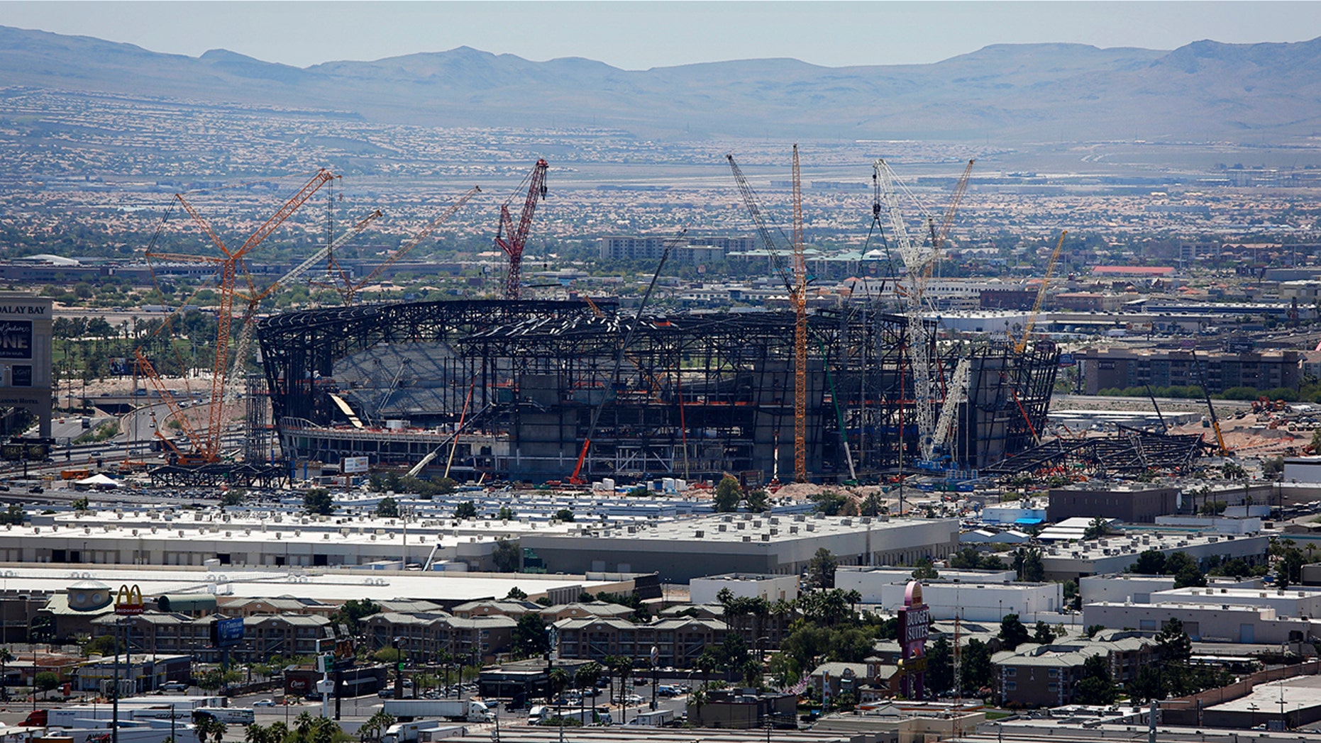 FILE - In this June 4, 2019, file photo, construction cranes surround the football stadium under construction in Las Vegas. The $1.9 billion stadium being built in Las Vegas for the relocated NFL Raiders team is being named for Allegiant Travel Co. Officials made the announcement Monday, Aug. 5, 2019, during a ceremony marking installation of the final steel beam for the roof of the 65,000-seat indoor stadium just off the Las Vegas Strip. (AP Photo/John Locher, File)